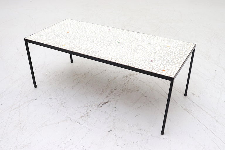 White glass mosaic tile coffee table with some multicolored accent tiles and black enameled metal frame. In original condition with wear appropriate to age and use.