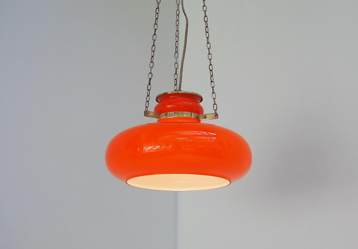 Orange glass pendant hanging elegantly in 3 brass chains including a suspension made in solid brass. The design gives a modern expression but still with the sought-after look of the 1960´s.

The mix of the white innerside and the orange outerside