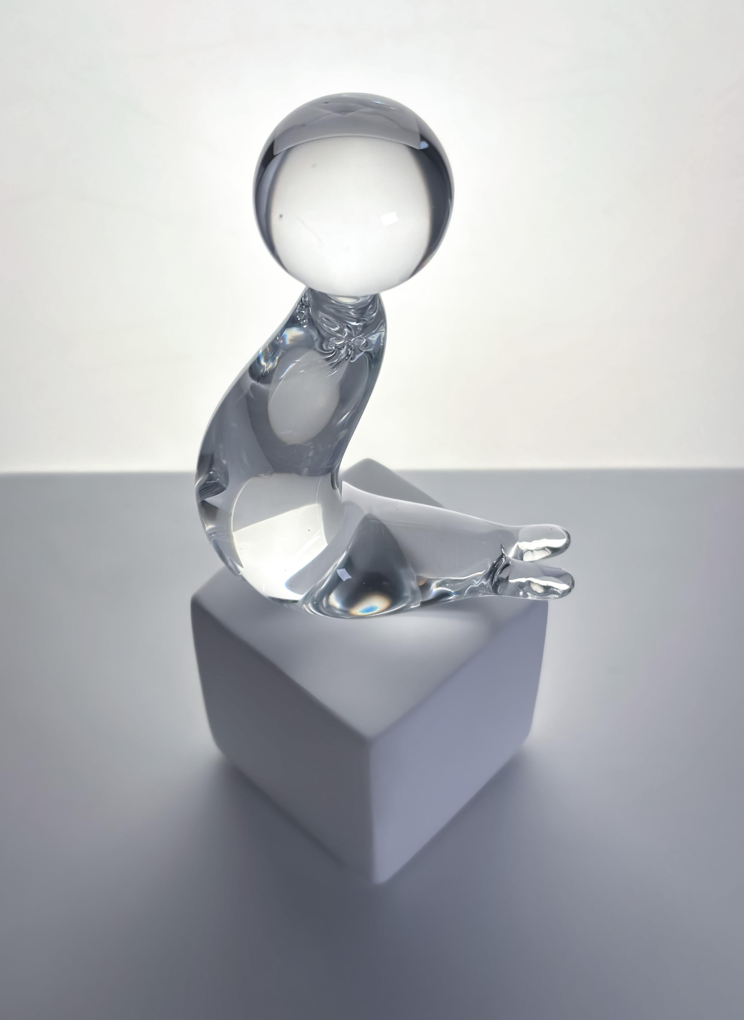 A modernist-style sea lion paperweight, crafted in the 1960s by Swedish glassmaker Folke Walving. 

Made from clear, sparkling lead crystal, the sculptural paperweight features a simple, curved body with subtle, impressed facial details and is