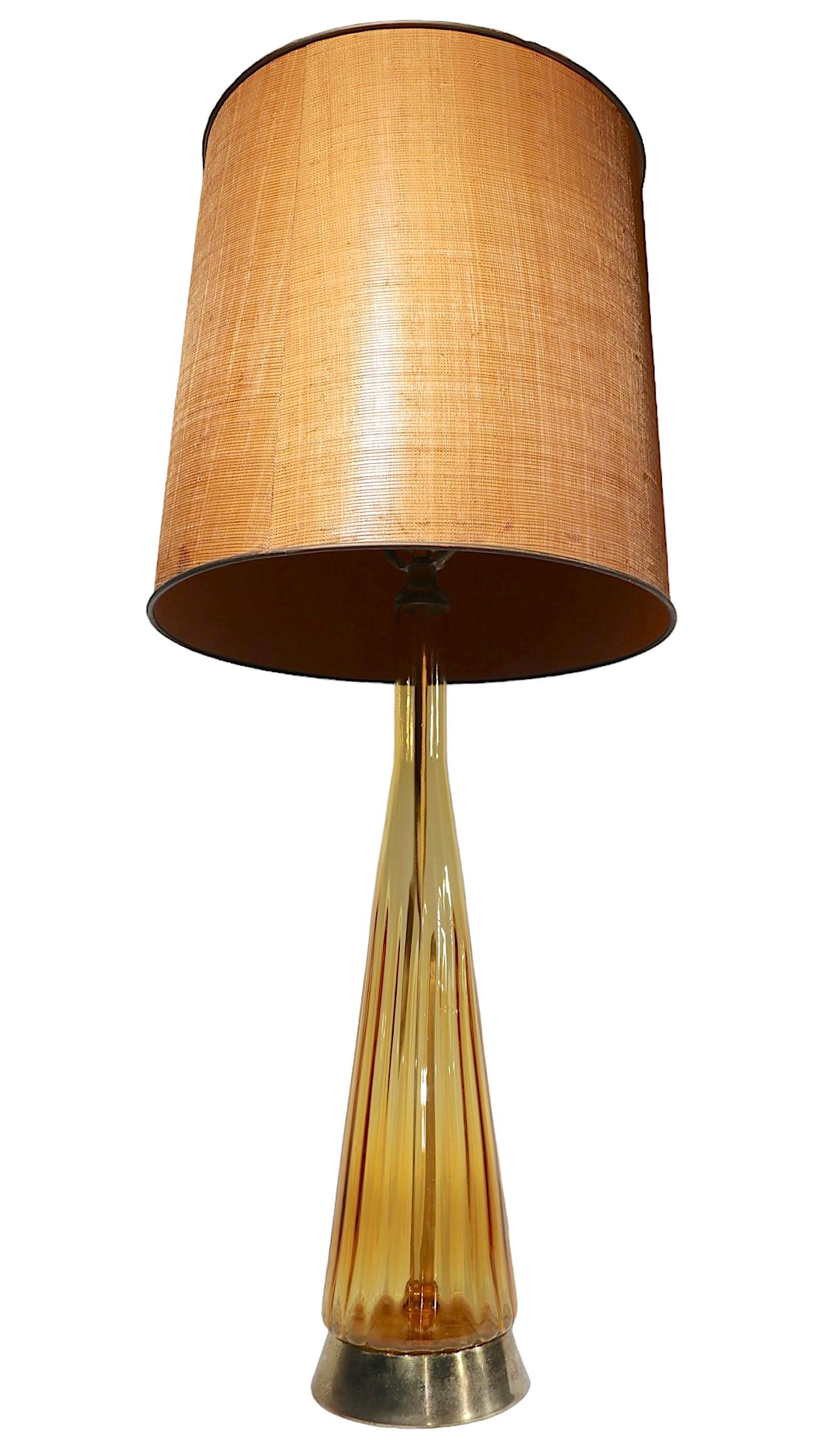 Mid Century  table lamp, having an elongated amber glass bottle form body, on a metal plinth base. The lamp is in very good, original, clean and working condition, showing only light cosmetic wear, normal and consistent with age, shade not included.