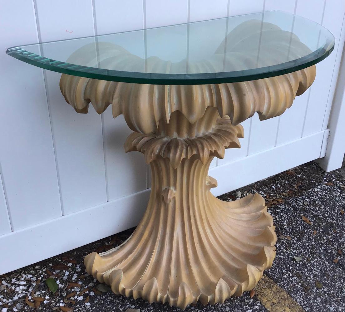 Mid-century wood console table carved with down swept fronds under the glass top. And along the bottom the fronds are carved turning up. Finished in a natural wood with a very slight washed look. A sturdy console table with beautiful form.