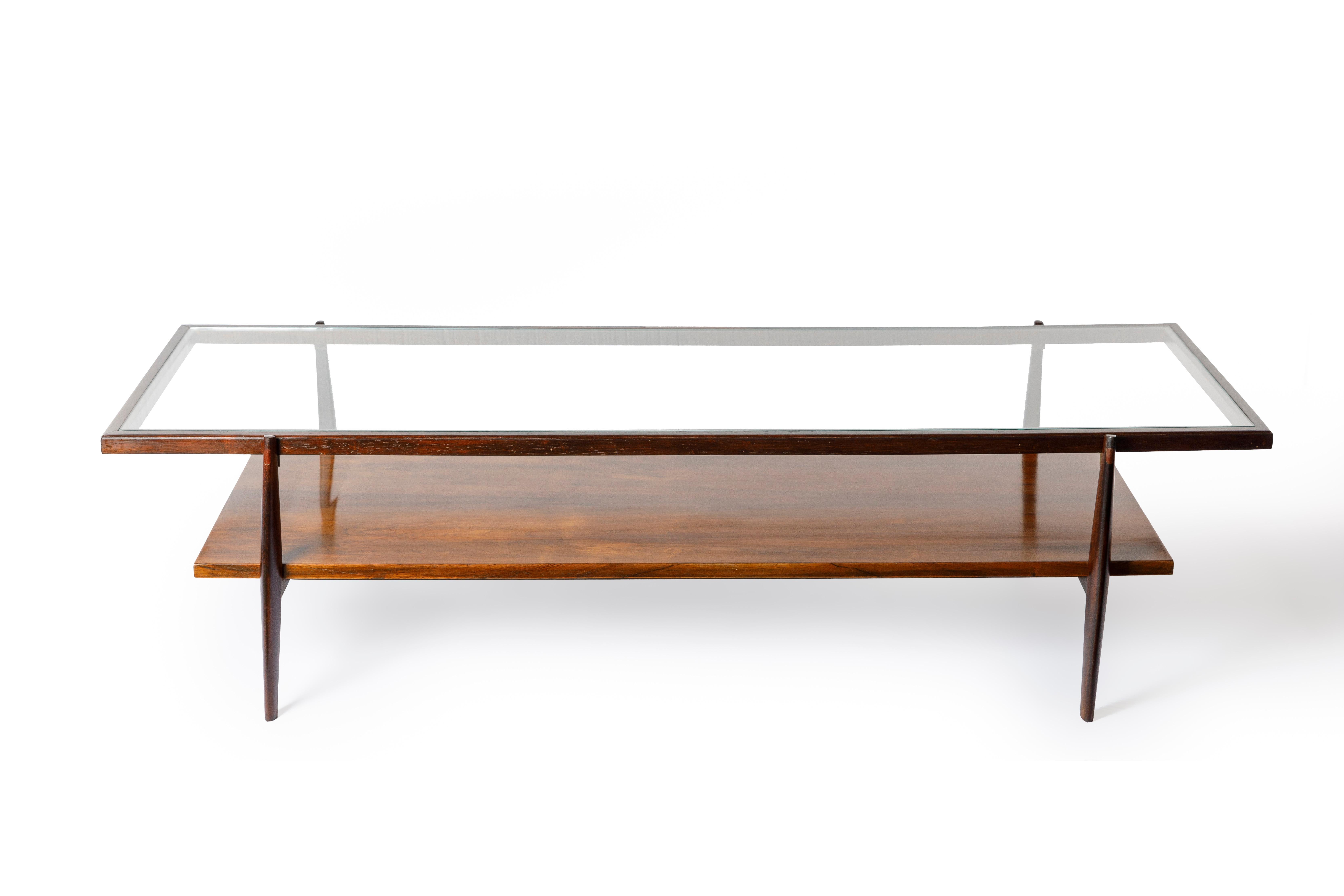 Elegant Mid-Century Modern coffee table manufactured in the 1950s by Liceu de Artes e Ofícios. Structured in solid Brazilian hardwood with a nestled glass top, this piece features turned legs and a single low shelf in veneered hardwood, perfect for