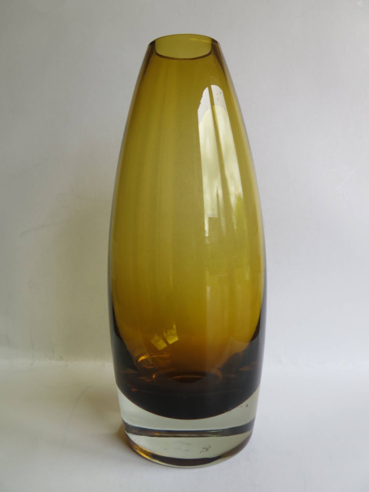 This is a mid-century Scandinavian-modern, Art glass vase, attributed to the designer Tamara Aladin, for the maker Riihimaen / Riihimaki Lasi Oy of Finland.

The vase has a lovely cylindrical tapering form in a cased Amber-Topaz Yellow and clear
