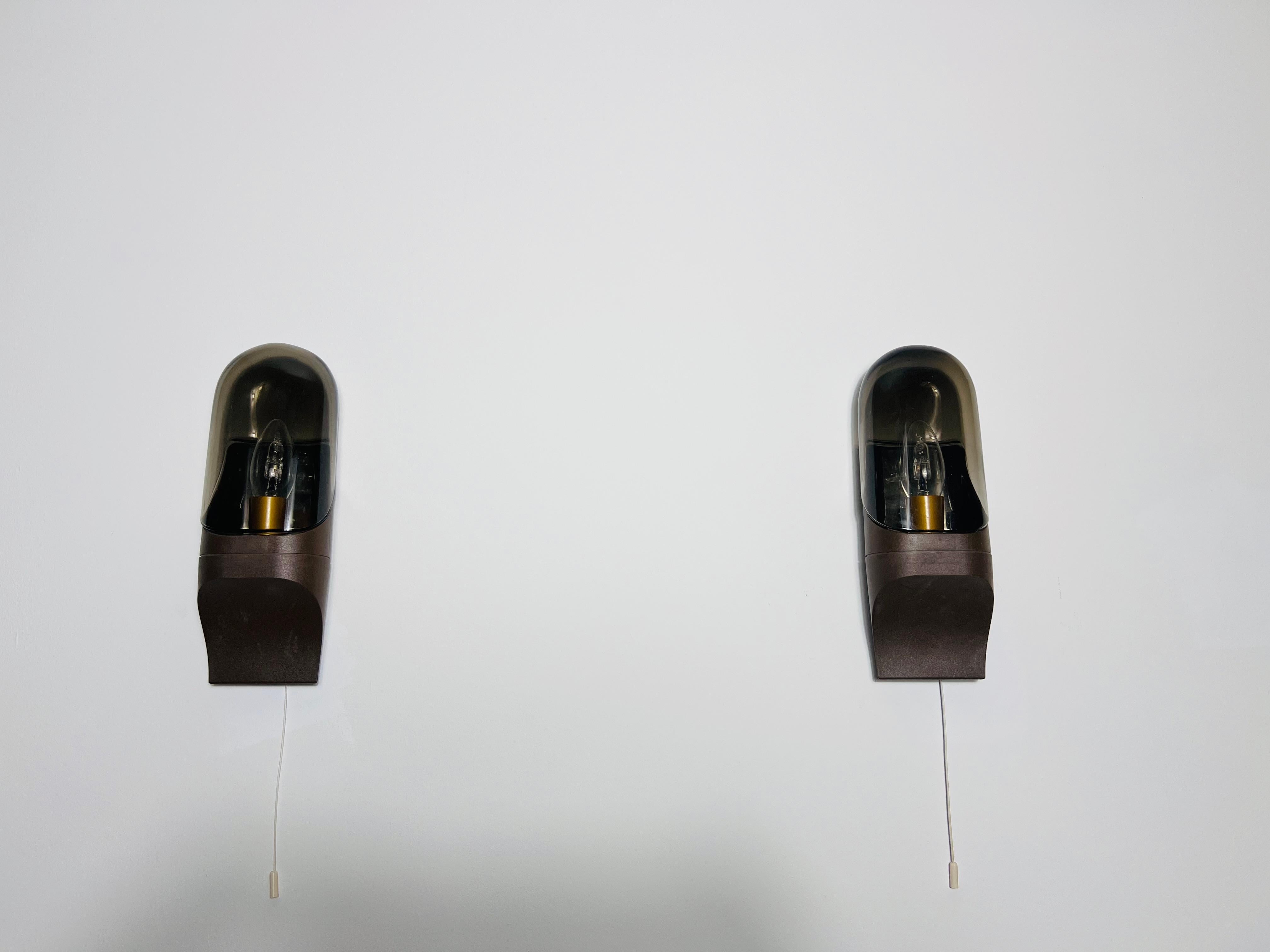These space age wall lamps werr designed by Hillebrand in the 1970s and are crafted from high-quality glass and plastic. Its refined, luxurious design effortlessly enhances any interior space. The lamp emits a soft, diffused glow, creating a warm