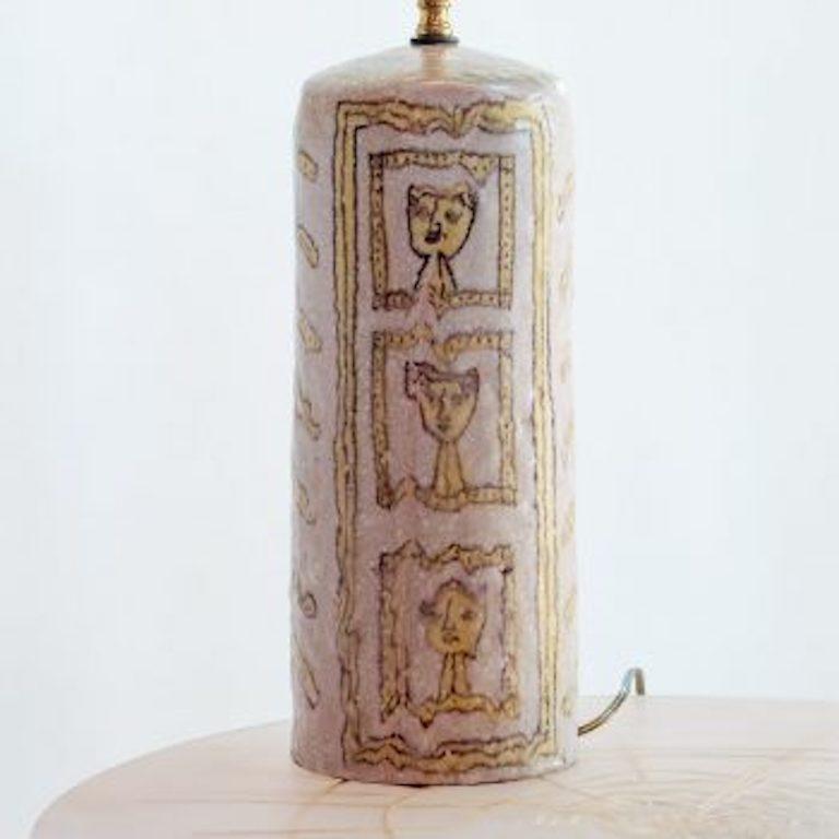 Glazed ceramic table lamp hand-decorated with Picasso-esque portrait faces. Yellow and white with lavender-gray. New linen shade and rewired with brown nylon cord. Signed 