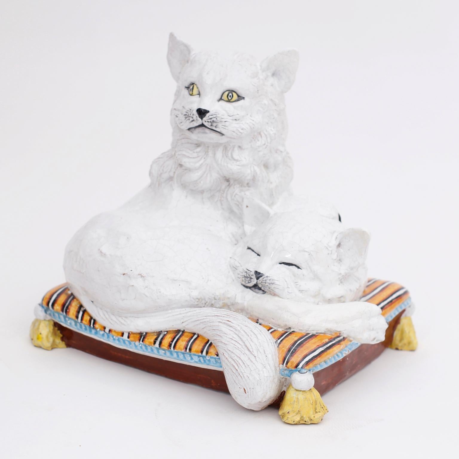 Charming Italian crackle glazed terracotta sculpture of two white cats on a striped pillow with tassels.