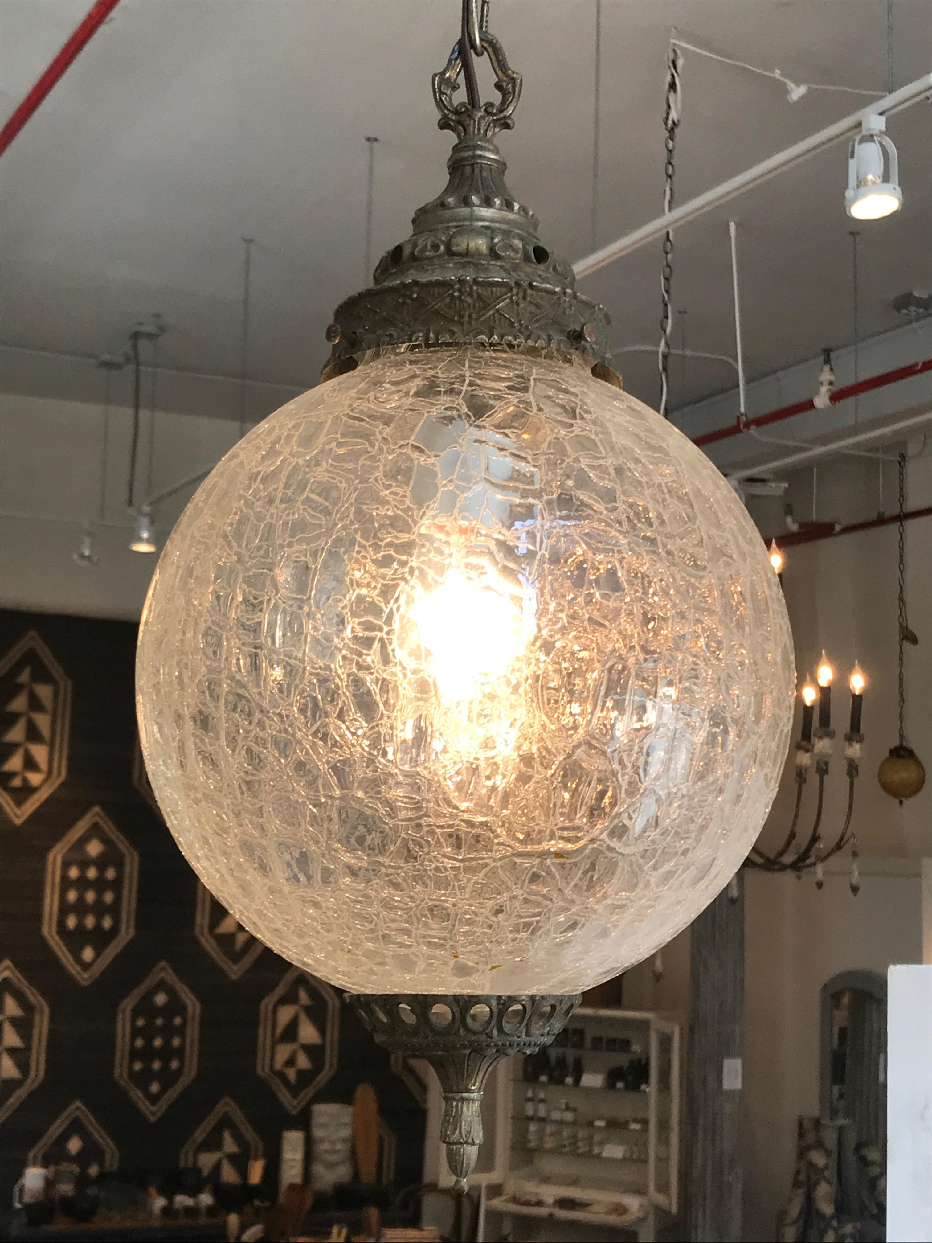 A beautiful midcentury globe pendant with clear textured glass, texture that mimics shattered glass. Subtle detailed brass encasing to finish the pendant.