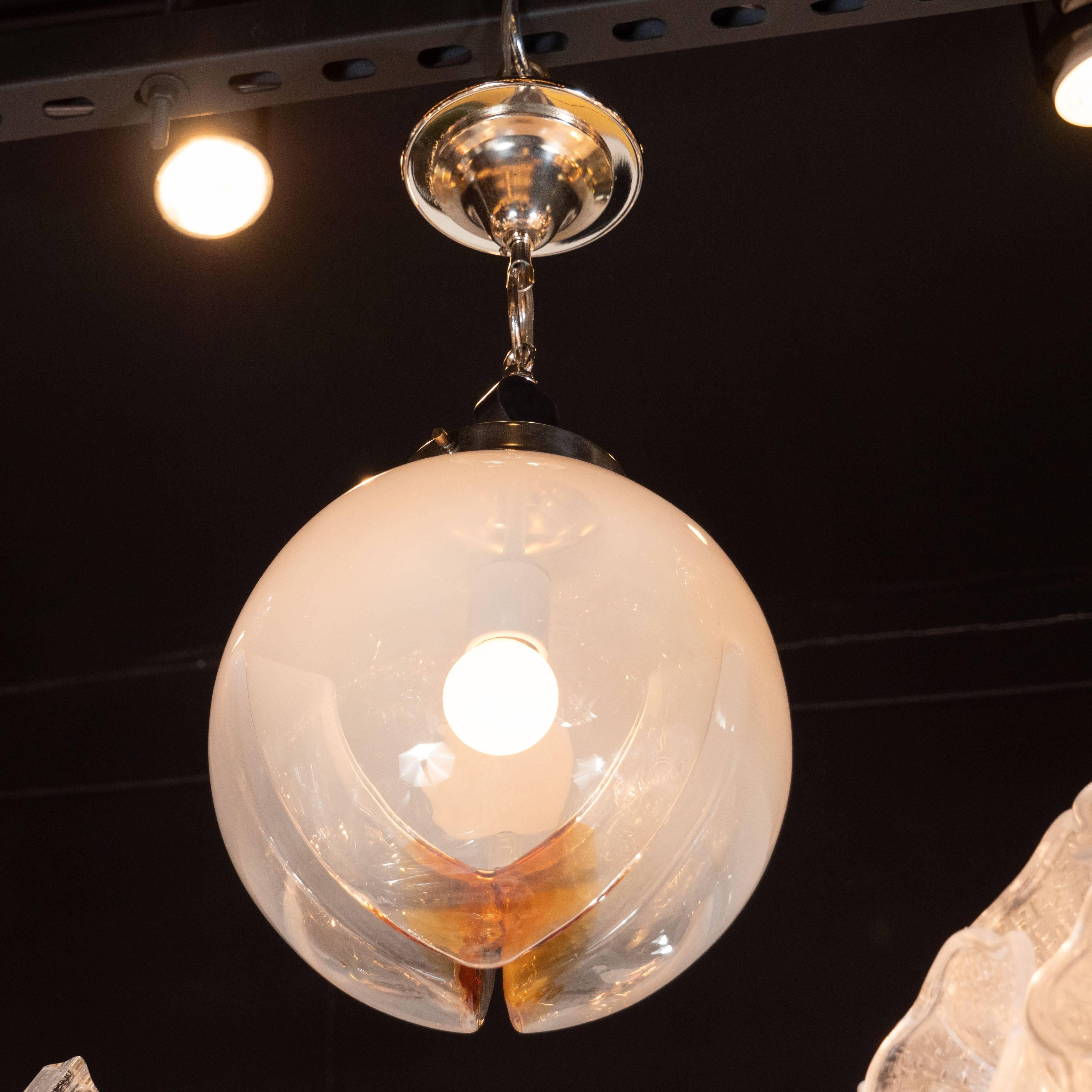 This refined globe pendant was realized by the celebrated maker Mazzega in Italy, circa 1970. It features a globular form in semi opaque glass with amber inflections and channel detailing at the bottom that wraps around three of the sides. Above the