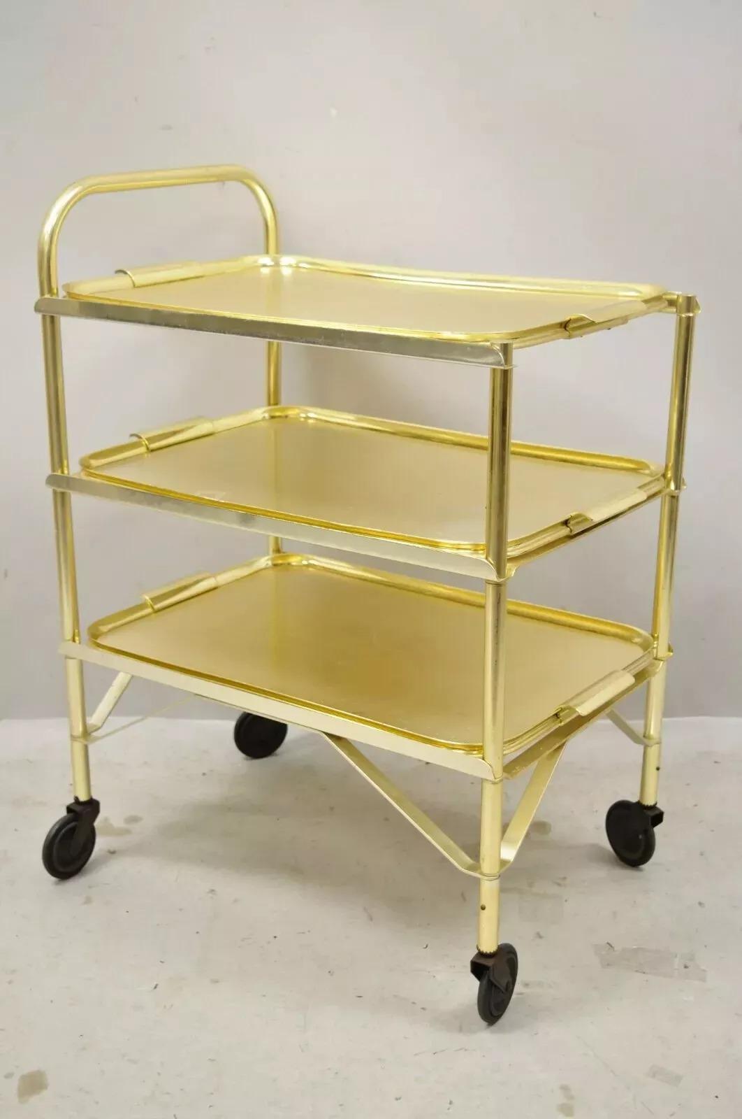 Vintage Mid Century Modern Gold Aluminum Metal Folding Rolling Bar Cart Server with 3 Trays. L'articolo è dotato di 3 vassoi rimovibili, rotelle, struttura in alluminio fuso, linee pulite e moderniste, grande stile e forma. Circa metà del XX secolo.