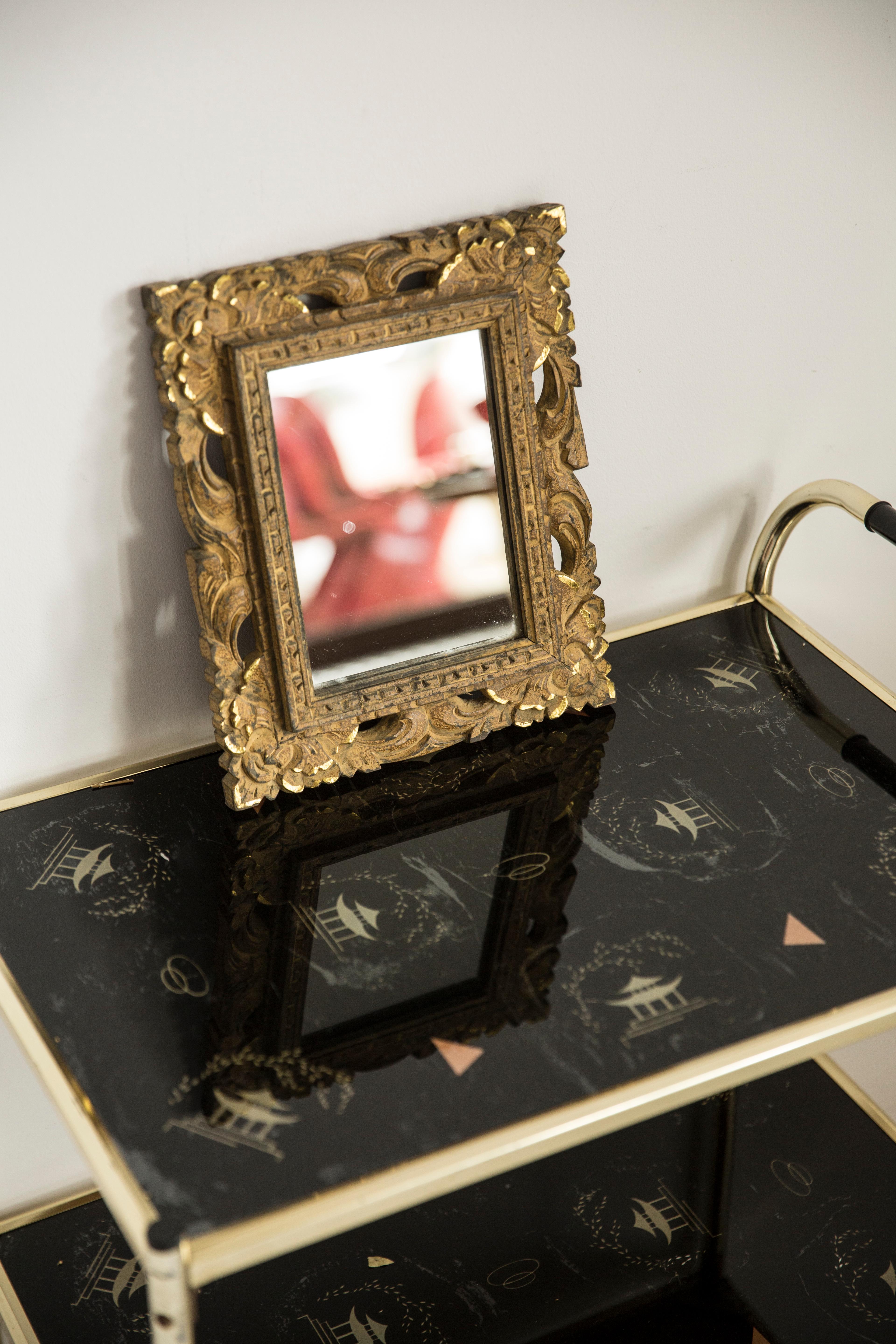 Un bellissimo specchio in una cornice decorativa dorata con fiori motive dall'Italia. La struttura è realizzata in Wood. Lo specchio è in ottime condizioni vintage, senza danni o crepe nella cornice. Vetro originale. Un pezzo davvero unico per ogni