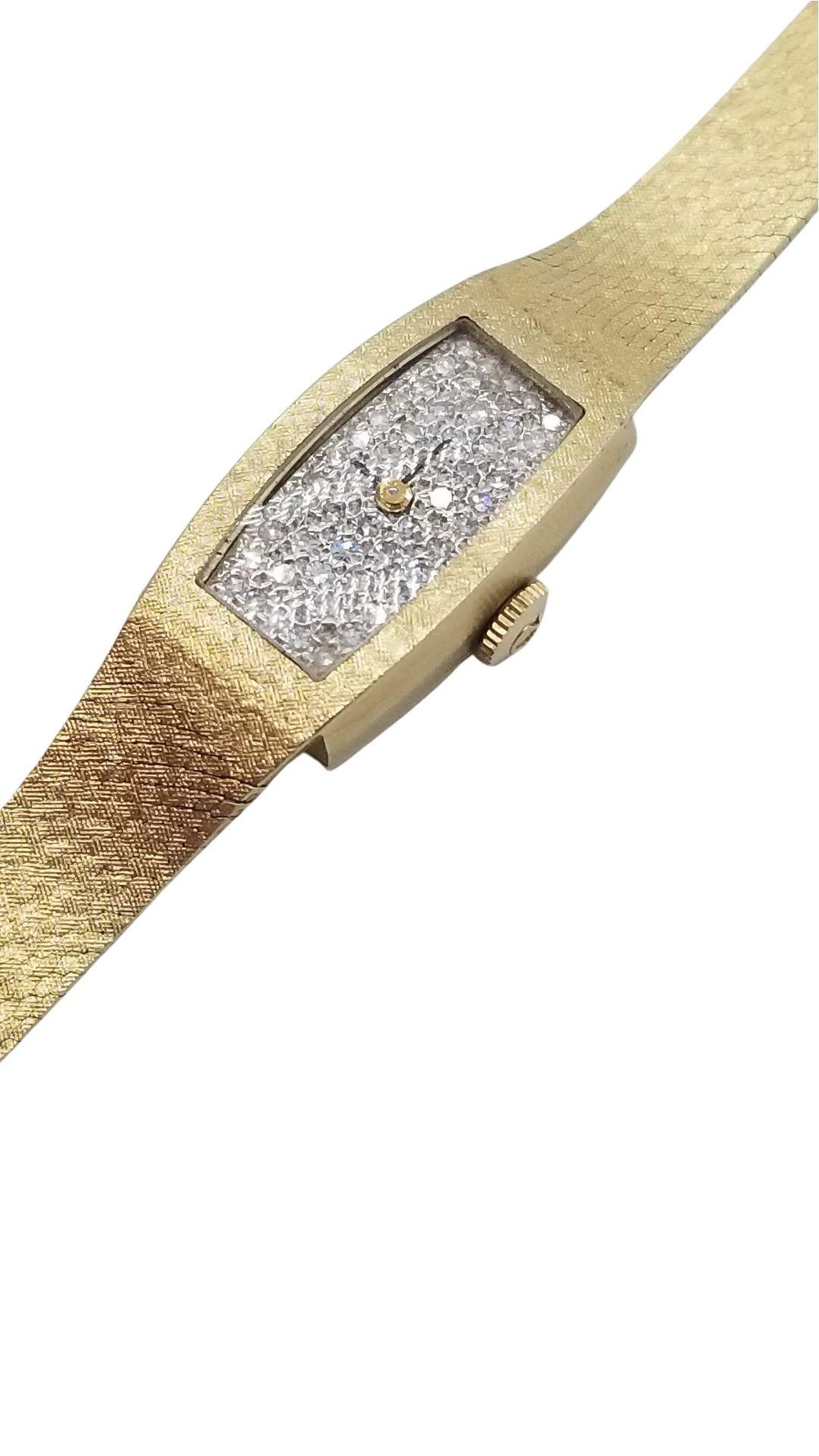 Vintage 1960 14k gold Omega women's wristwatch with a diamond-encrusted watch face containing over 20 1ct diamonds and features a manual wind movement. The movement has been serviced and keeps time well. The watch is 7.5