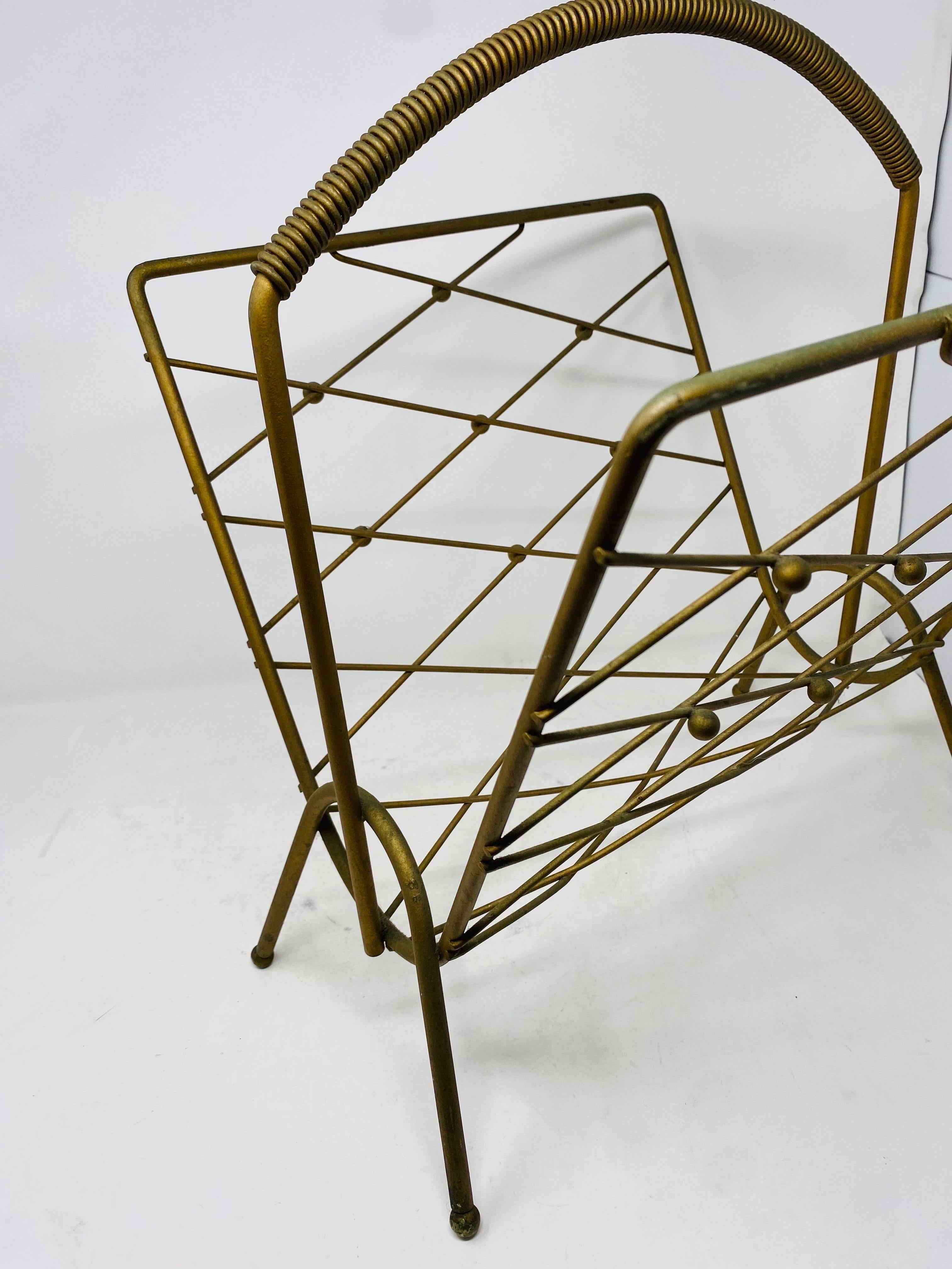 Beautiful Mid Century sculptural gold record sling/magazine rack.  This great piece works great with a variety of decors and styles.  Sculptural top handle with crossed motif sides.  Stylized legs and accents.

Mid-Century, Hollywood Regency, Art