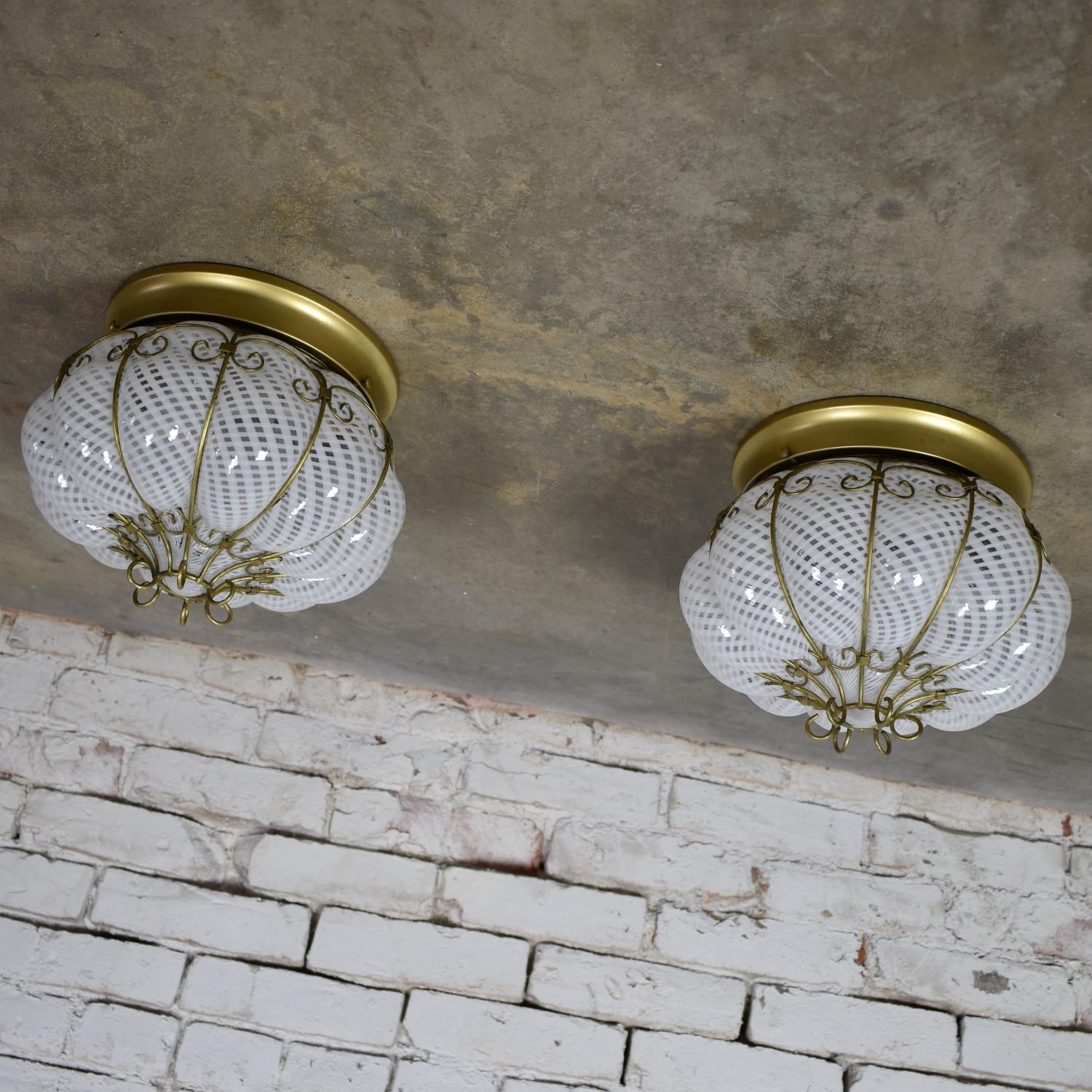 Fabulous pair of midcentury Venetian caged latticino glass ceiling lights in white and gold. They can also be used as wall sconces as the globes are held tight to the fixture with screws. They are in fabulous vintage condition and have new wiring