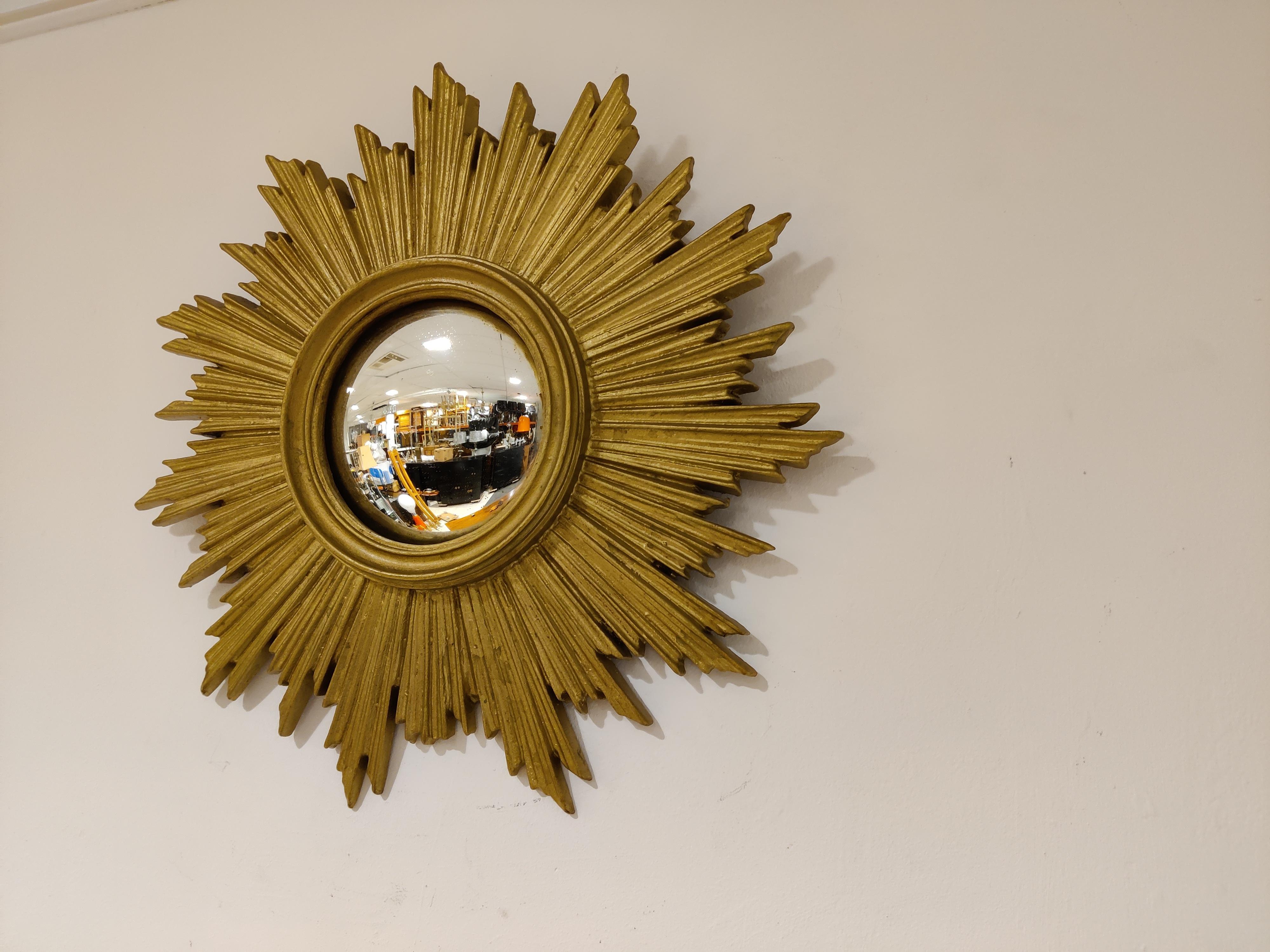 Gilded resin sunburst mirror with convex mirror glass.

The golden mirror is in a good overall condition with one small damage which is not very disturbing.

Beautiful eye catching mirror.

1960s - Belgium

Dimensions:

Diameter: