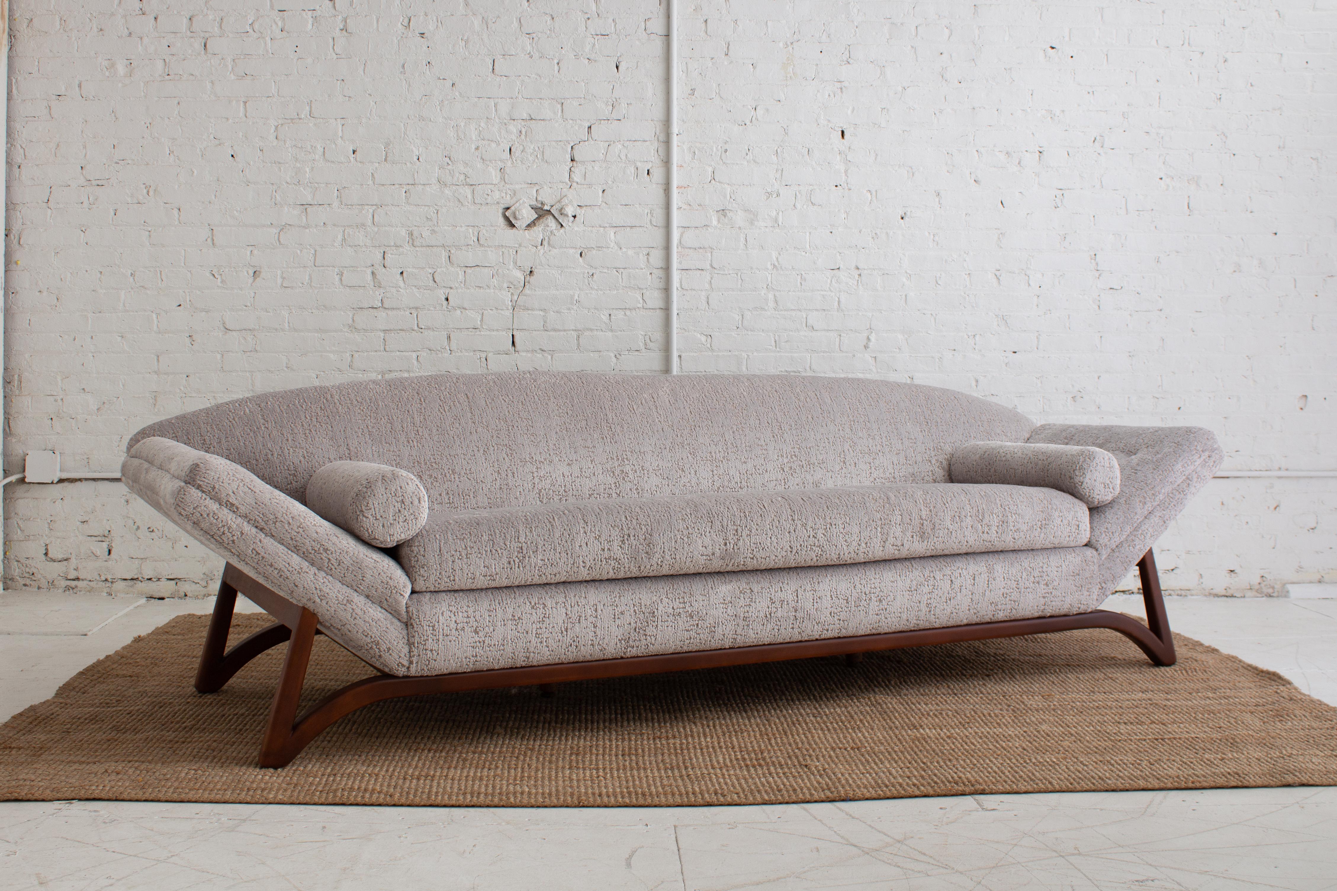 A Mid-Century Modern “gondola” sofa in the style of Adrian Pearsall. Complete with tufted arms and bolster pillows. Newly restored. Upholstered in Holly Hunt “Plushy,” a silver and beige textured chenille. New foam and refinished frame.