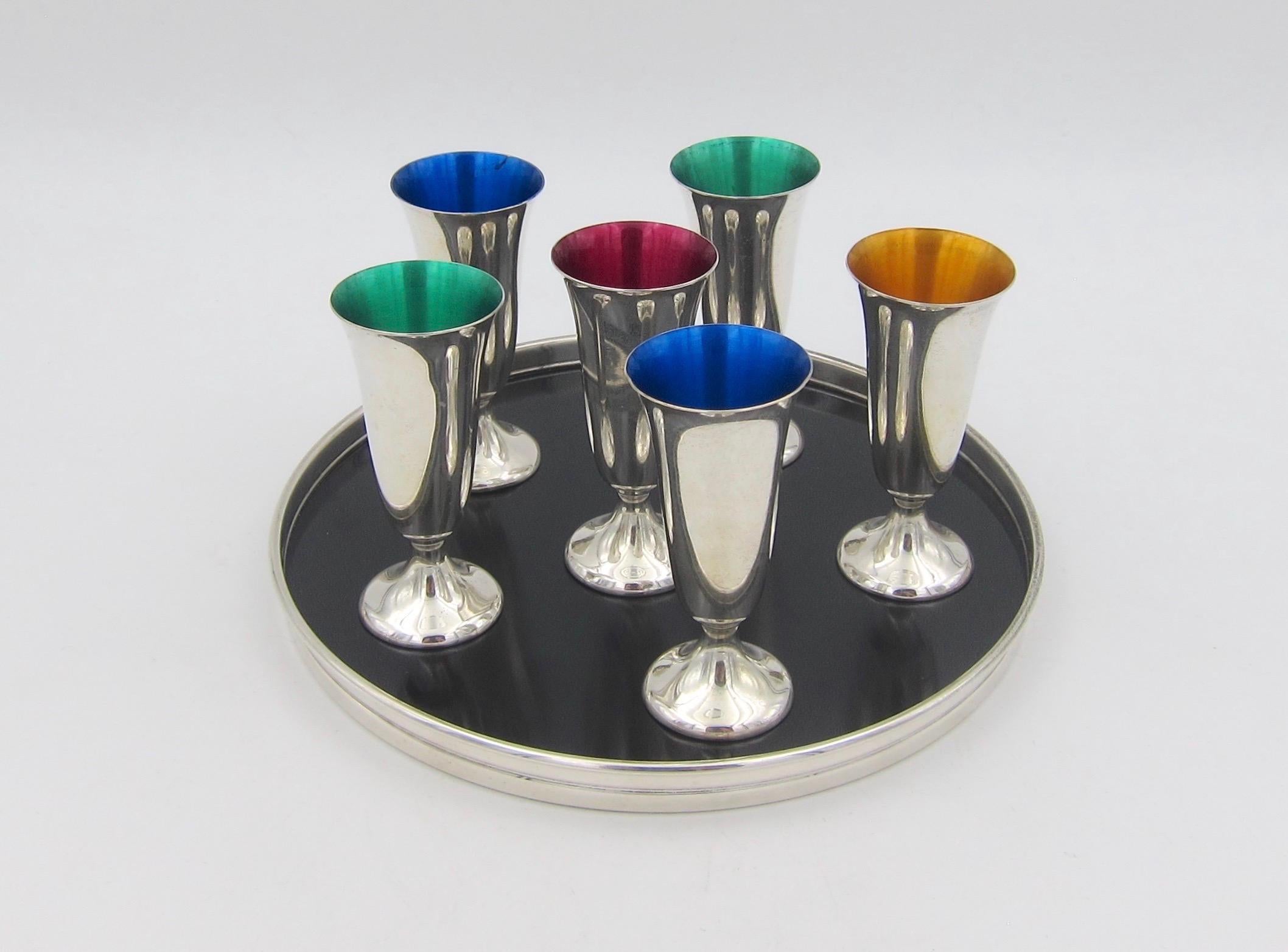 A seven-piece midcentury vodka or cordial set in sterling silver with jewel-toned interiors of gold, red, blue, and green from Gorham Manufacturing Company of Providence, Rhode Island. 

The urn-shaped footed cordials measure 2.74 in. height x 1.25