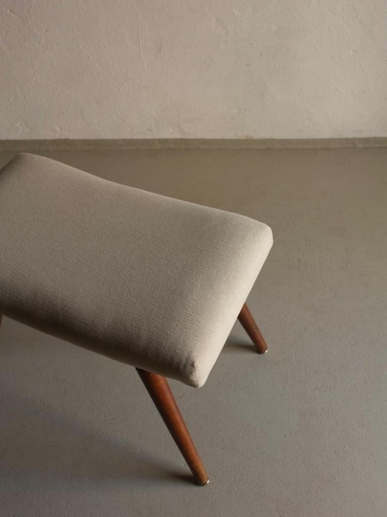 Mid-century low stool or ottoman with gray cotton upholstery.

Additional information:
Country of manufacture: Sweden
Period: 1960s
Dimensions: 50 W x 29 D x  40 H cm
Condition: Good vintage condition, new cotton fabric upholstery
