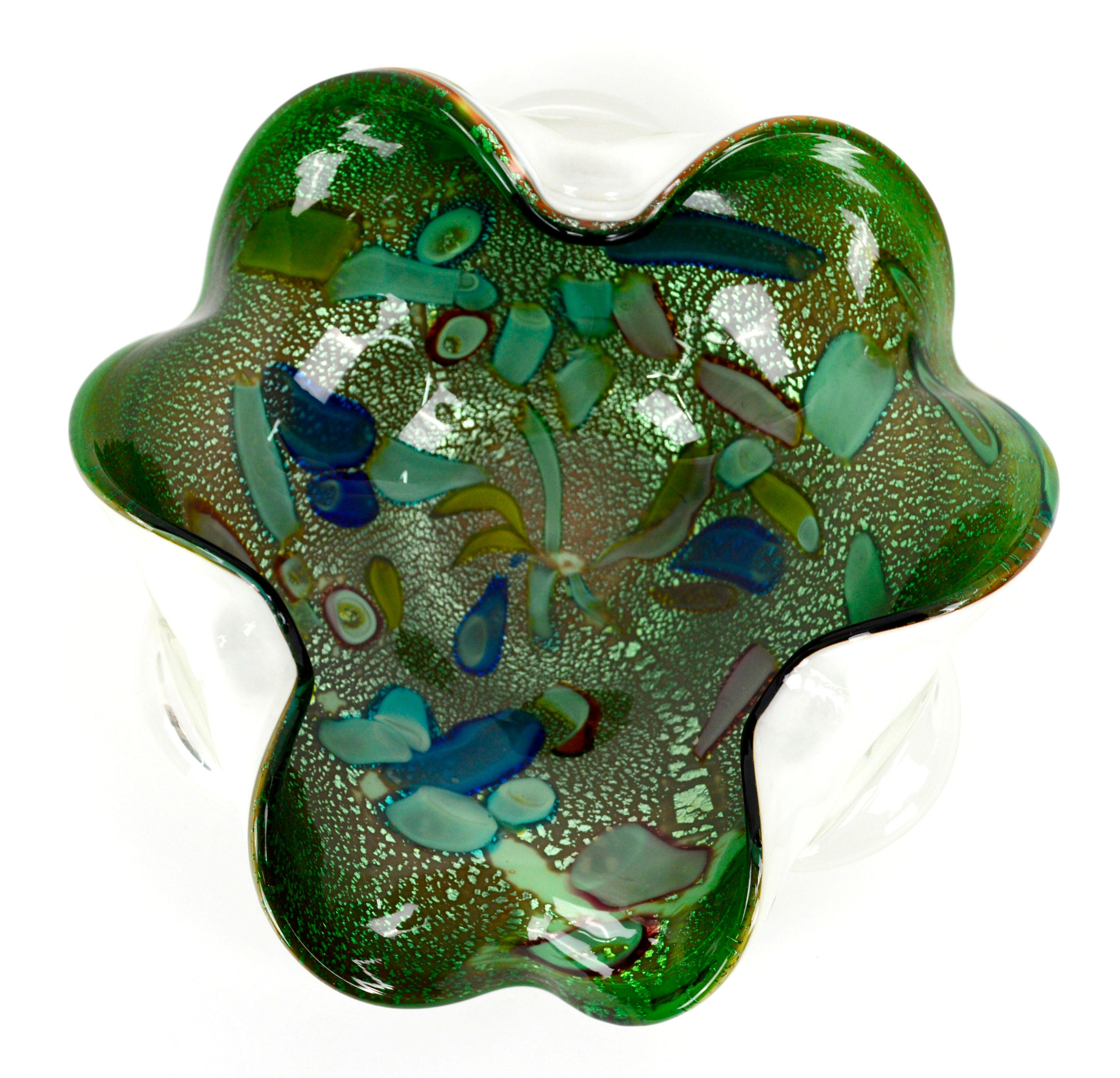 Beautiful hand blown Mid-Century Modern green and cyan murano glass ruffled bowl, decorated with iridescent Avventurina flecks and abstract geometric Murrina multi-colored shapes and forms. Folded edges catch the light and give this piece a dynamic,