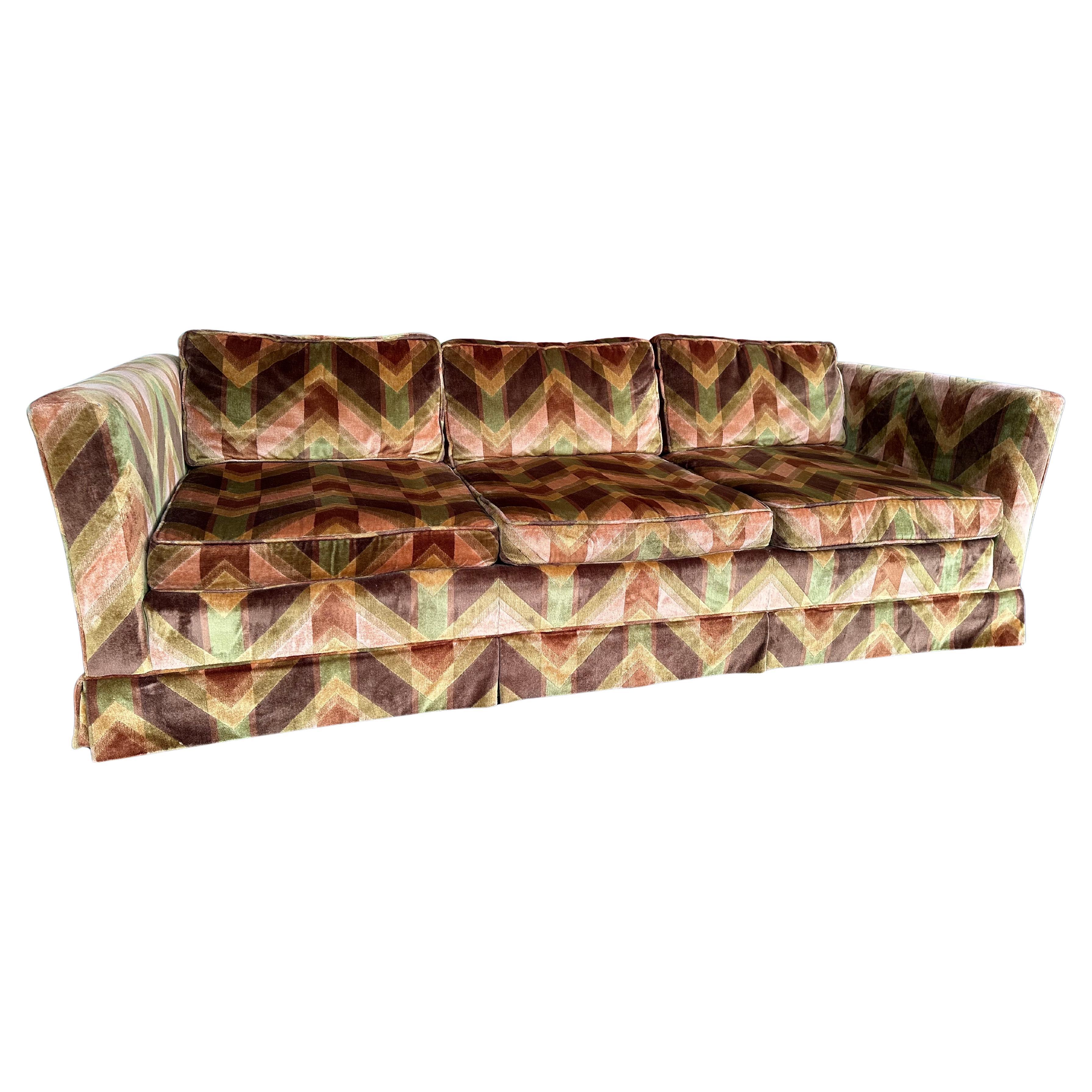 Vintage Mid Century Velvet Velour Sofa in shades of green, peach and brown in a geometric chevron pattern. Soft and comfortable three seat sofa made by Sherrill furniture of Hickory NC. Skirt can be removed if desired to reveal the wood legs. In