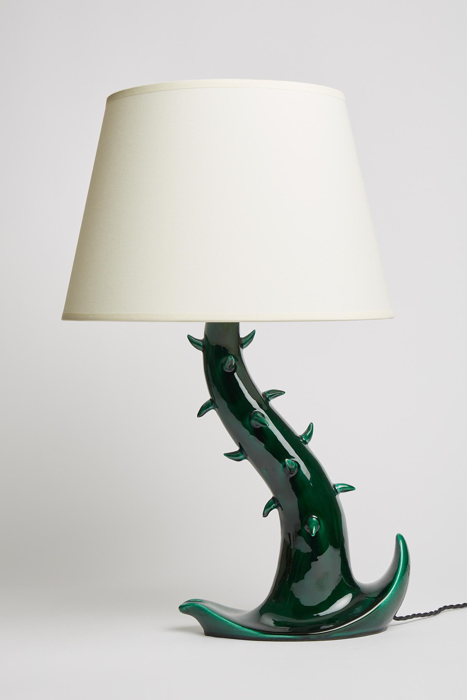 A deep green glazed ceramic table lamp stylised as a free form branch with thorns. 
Stamped ‘Françoise - Calanques des Issambres’. 
France, third quarter of the 20th Century. 
With the shade: 57 cm high by 35 cm diameter.
Lamp base only: 40 cm
