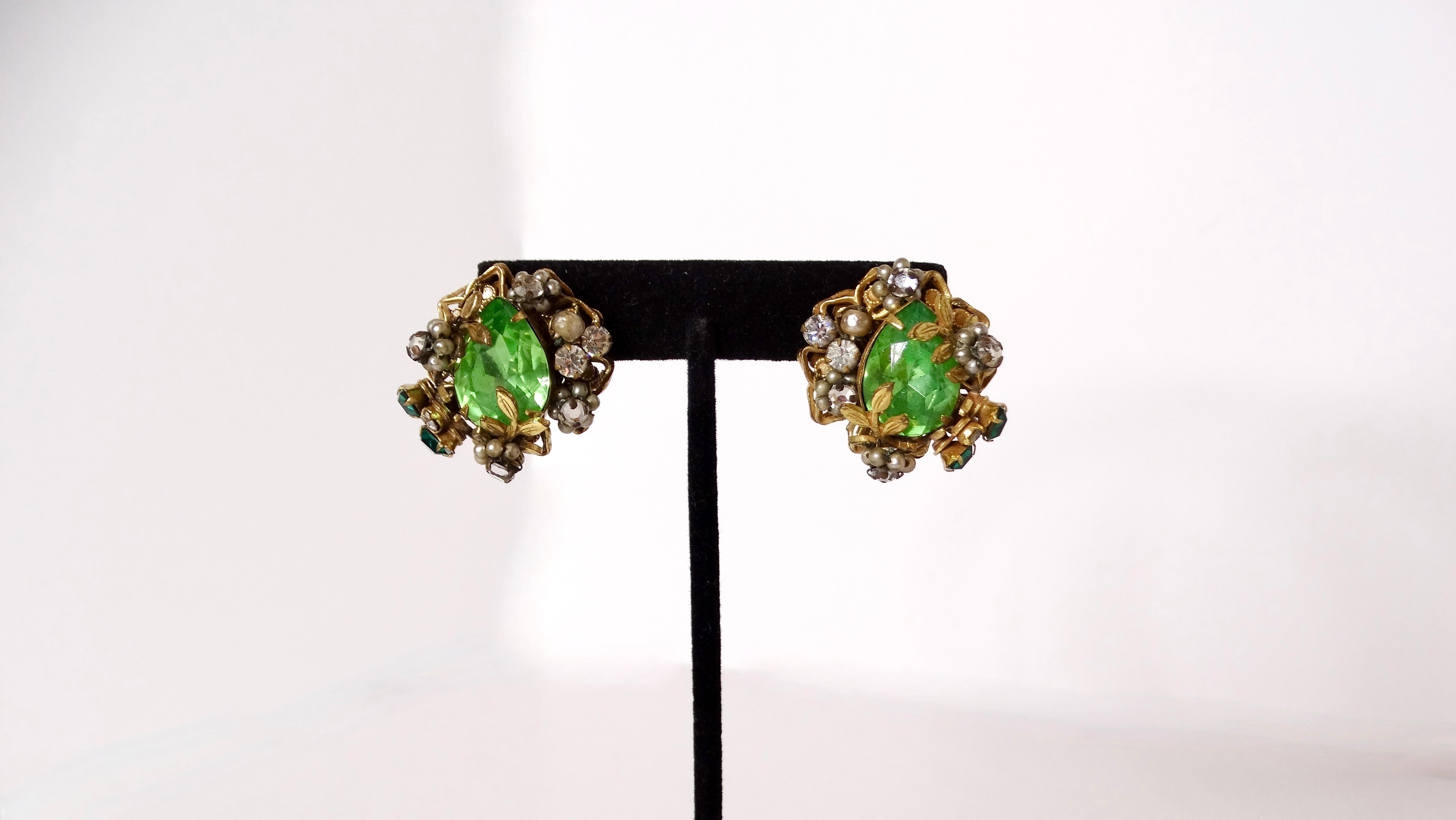 Embrace timeless elegance with these stunning Mid-Century Green Crystal 14k Gold Plated Cluster Clip-On Earrings. Inspired by nature’s beauty, these earrings feature intricate floral motifs adorned with radiant green crystals that sparkle with every