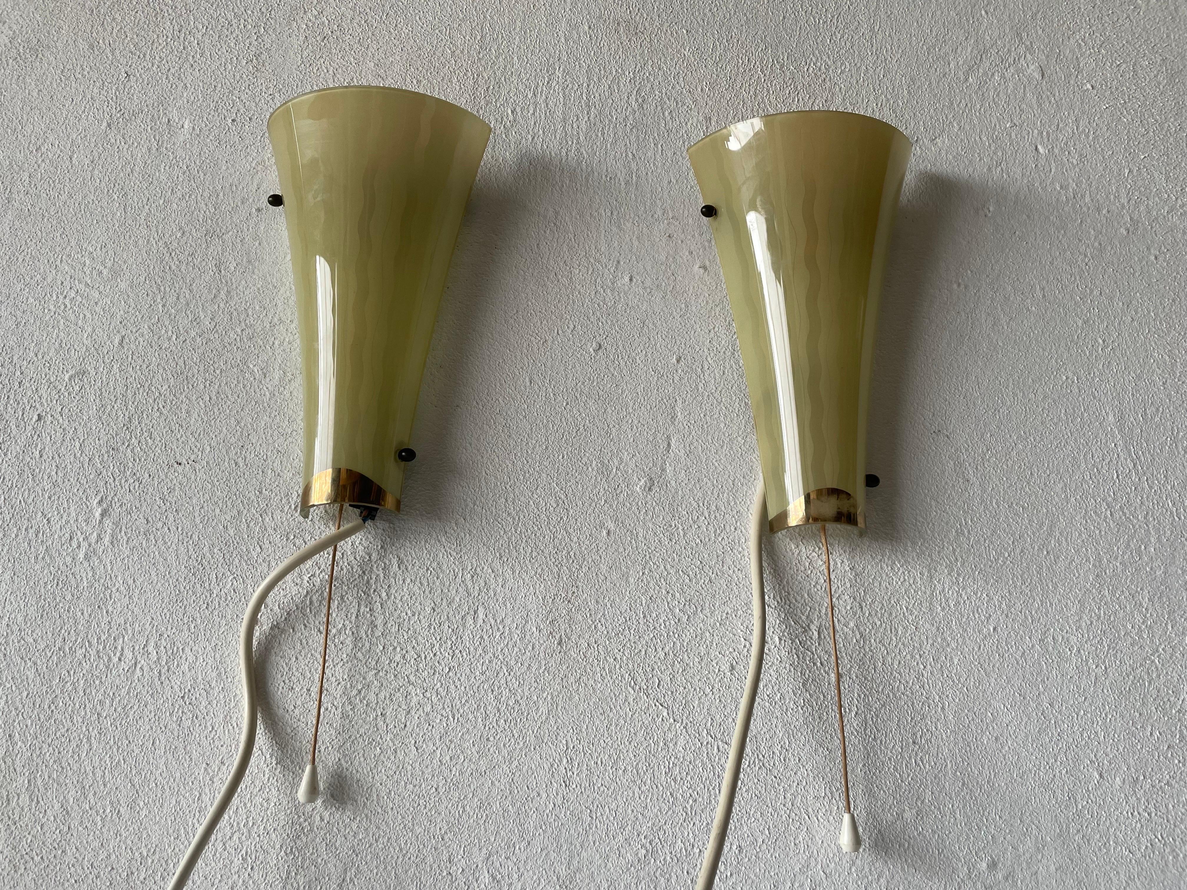 Mid-century Beautiful green curved glass pair of sconces, 1950s, Germany

Very elegant and Minimalist wall lamps
Lamp is in very good condition.

These lamps works with E14 standard light bulbs. 
Wired and suitable to use in all countries.