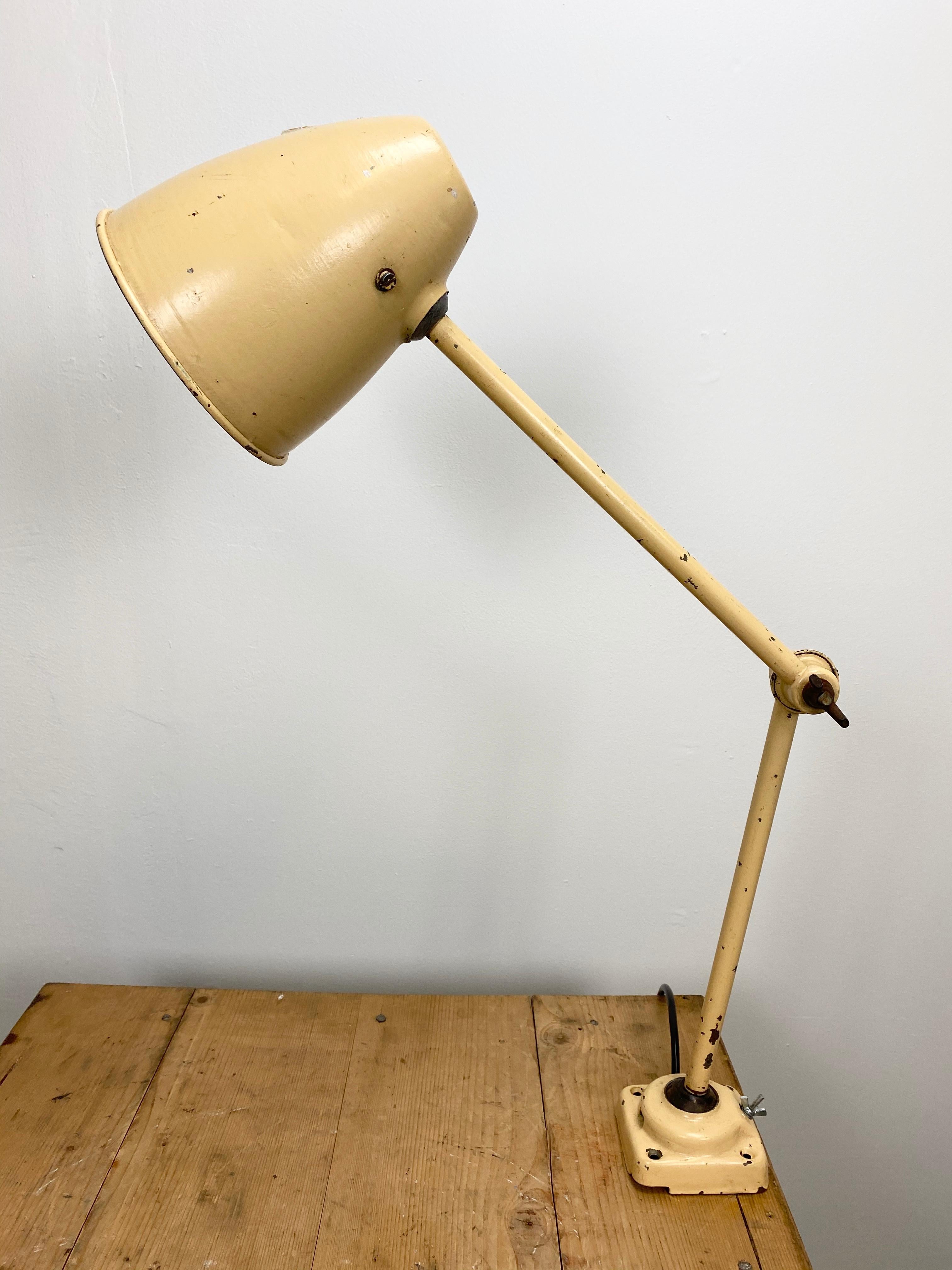 This beige industrial-style iron table lamp is made in former Czechoslovakia. It has an adjustable shade, three adjustable joints, a new porcelain socket for E 27 light bulbs and new wire. The switch is situated directly on the shade. Fully