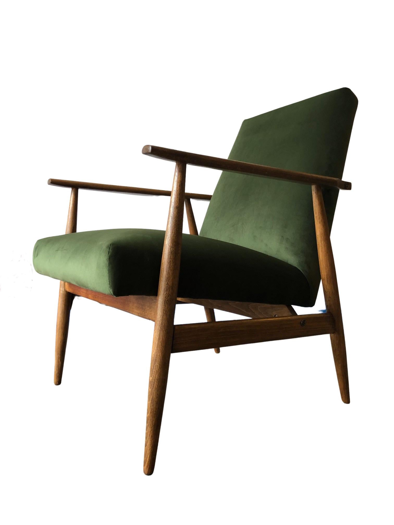 Le fauteuil conçu par Henryk Lis. La structure est réalisée en bois de hêtre dans une chaude couleur noyer, avec une finition en vernis satiné semi-mat. Le rembourrage est en velours de haute qualité dans une belle couleur verte. Le fauteuil a été
