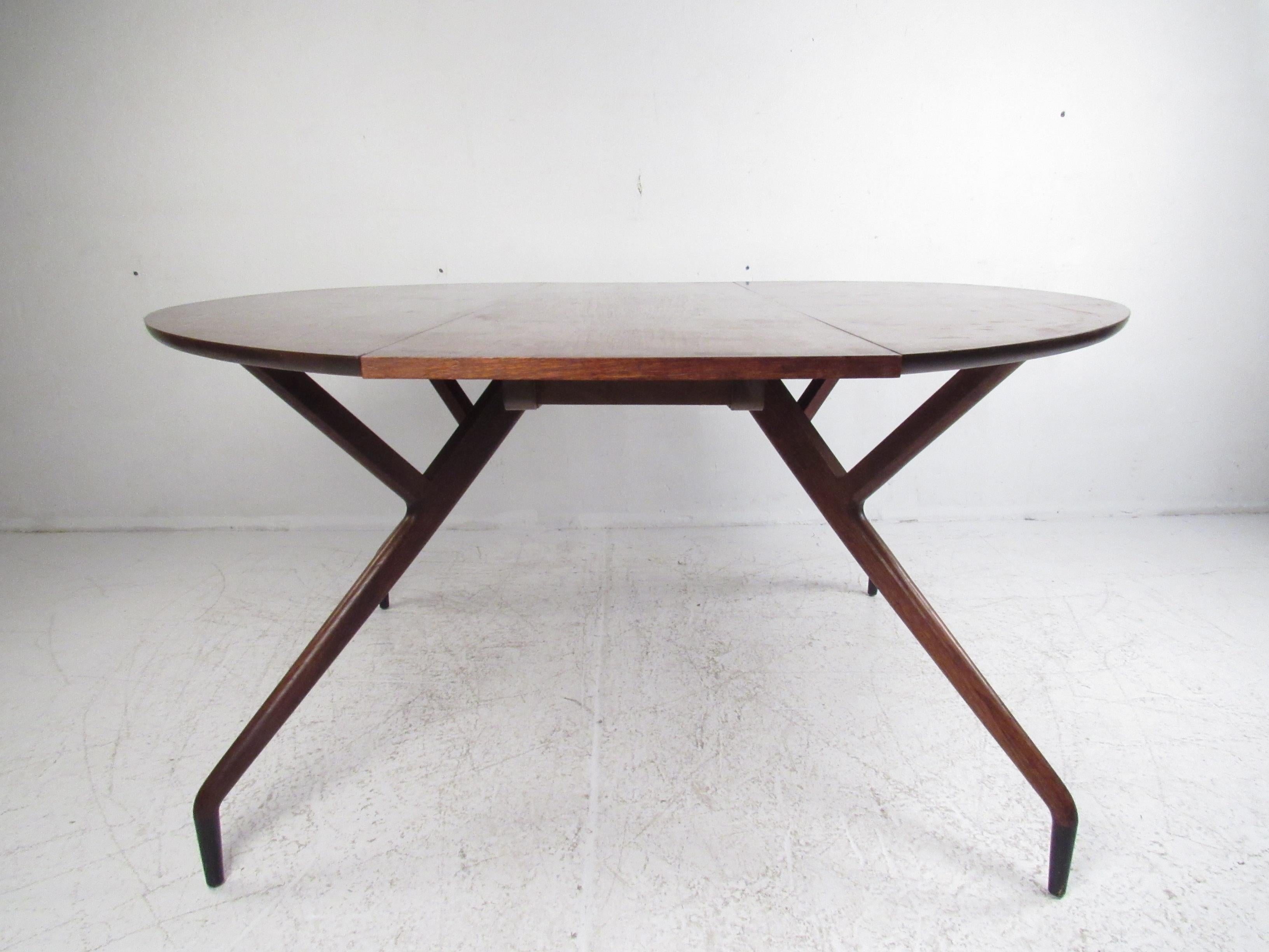 This beautiful vintage modern dining table features a convenient drop leaf design that allows the table to expand to 54 inches wide. Sturdy construction with a large table top that easily caters to many guests. The unusual spider legged base and
