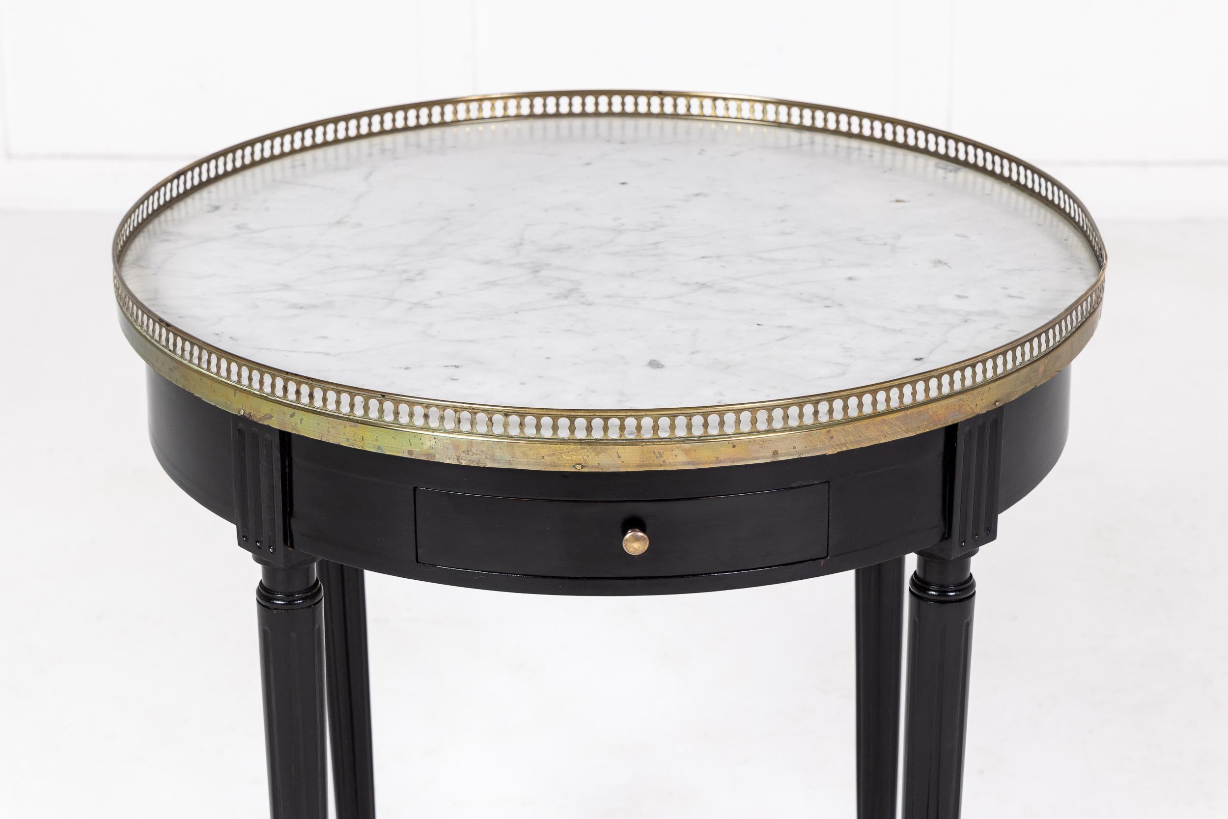 An elegant, small mid-century guéridon with white and grey veined marble top edged with a pierced brass gallery. The apron has two small drawers and two slides with small brass pull handles. Standing on four straight, tapering legs terminating in