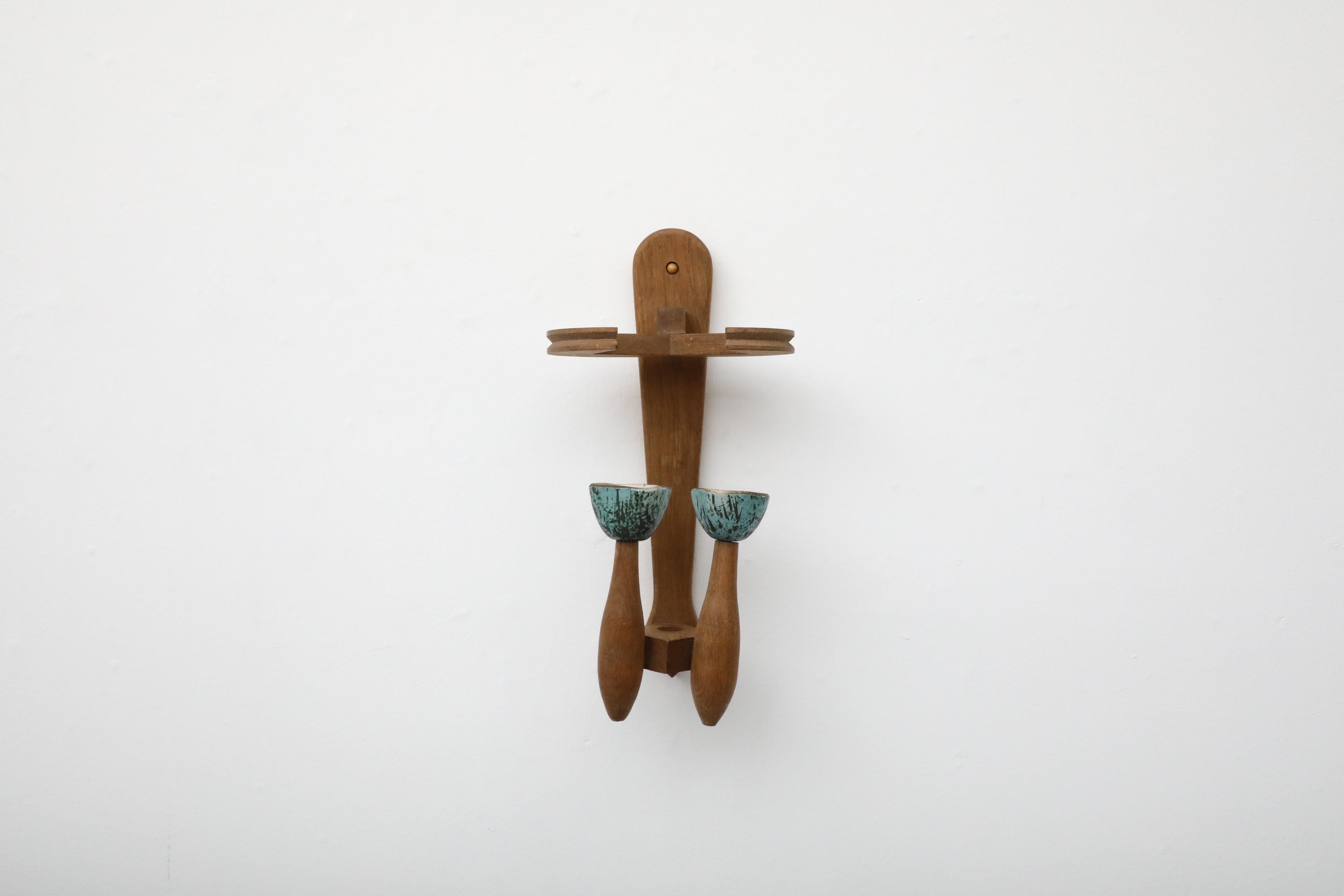 This French, Mid-Century modern wall sconce was designed by famed designer duo Guillerme et Chambron and is a classic and beautiful example of their iconic style. The sconce is made of oak and has two glazed ceramic holder in speckled teal that hold