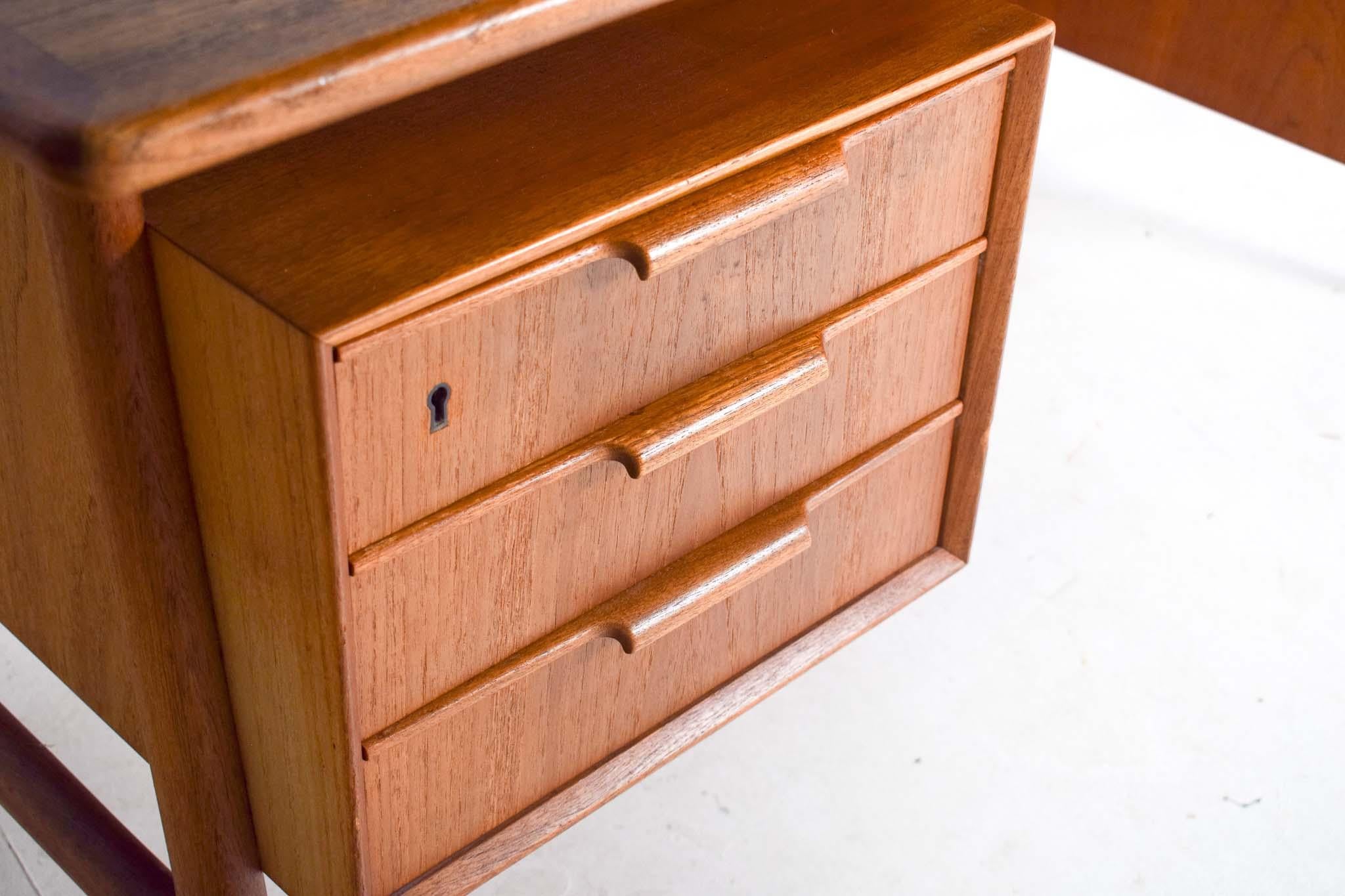 This mid-century teak desk, designed by Gunni Omann for Omann Jun, is a quintessential example of Danish modern design. Crafted in the 1960s, the desk embodies the clean lines and functional elegance characteristic of the era. The teak wood, known