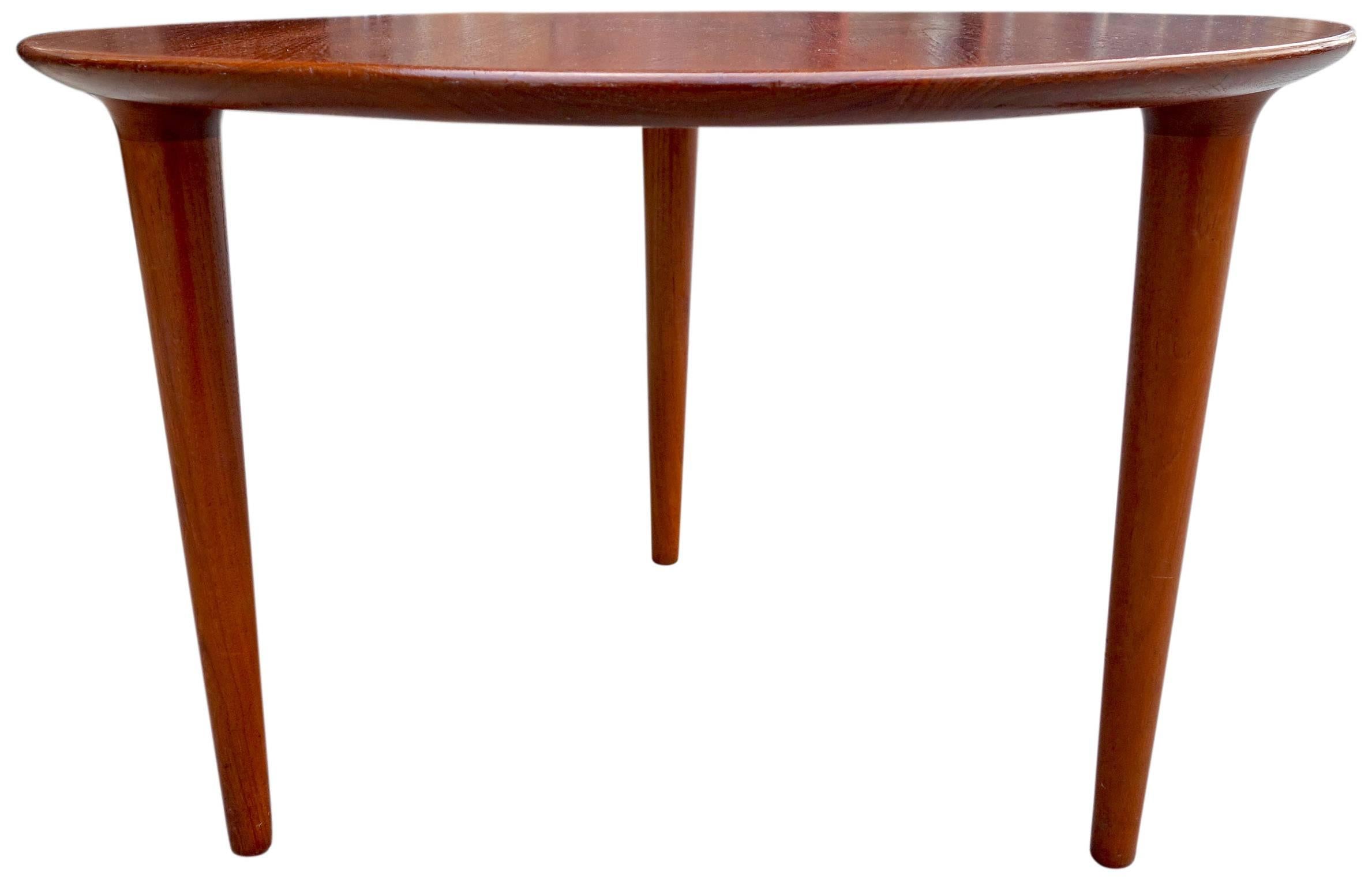 Elegant three legged round side or coffee table in solid teak. Showing minimal lines with reverse tulip tapered legs. Excellent proportions and craftsmanship make this table a must in any refined home. In original condition and ready for use.