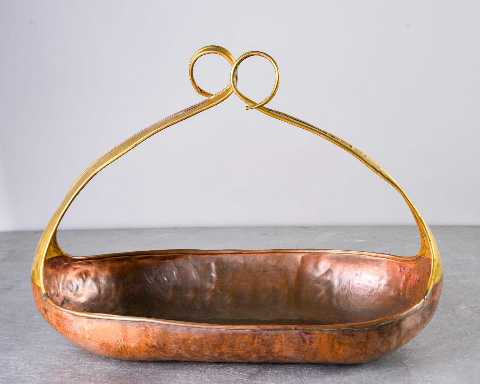Large circa 1960s handmade hammered copper and brass bowl with tall, tapered sides with scrolled ends that form a basket-like handle. Unknown maker. Found in Italy.