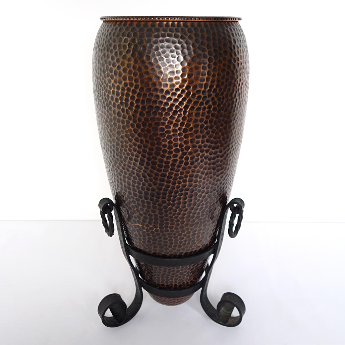 Umbrella stand made of hammered copper on a cast iron base probably dating from the 1950s. 
This sturdy yet elegant piece is a practical gem in your hallway or cloakroom. 
The amphora shaped umbrella stand sits in a heavy cast iron standard which