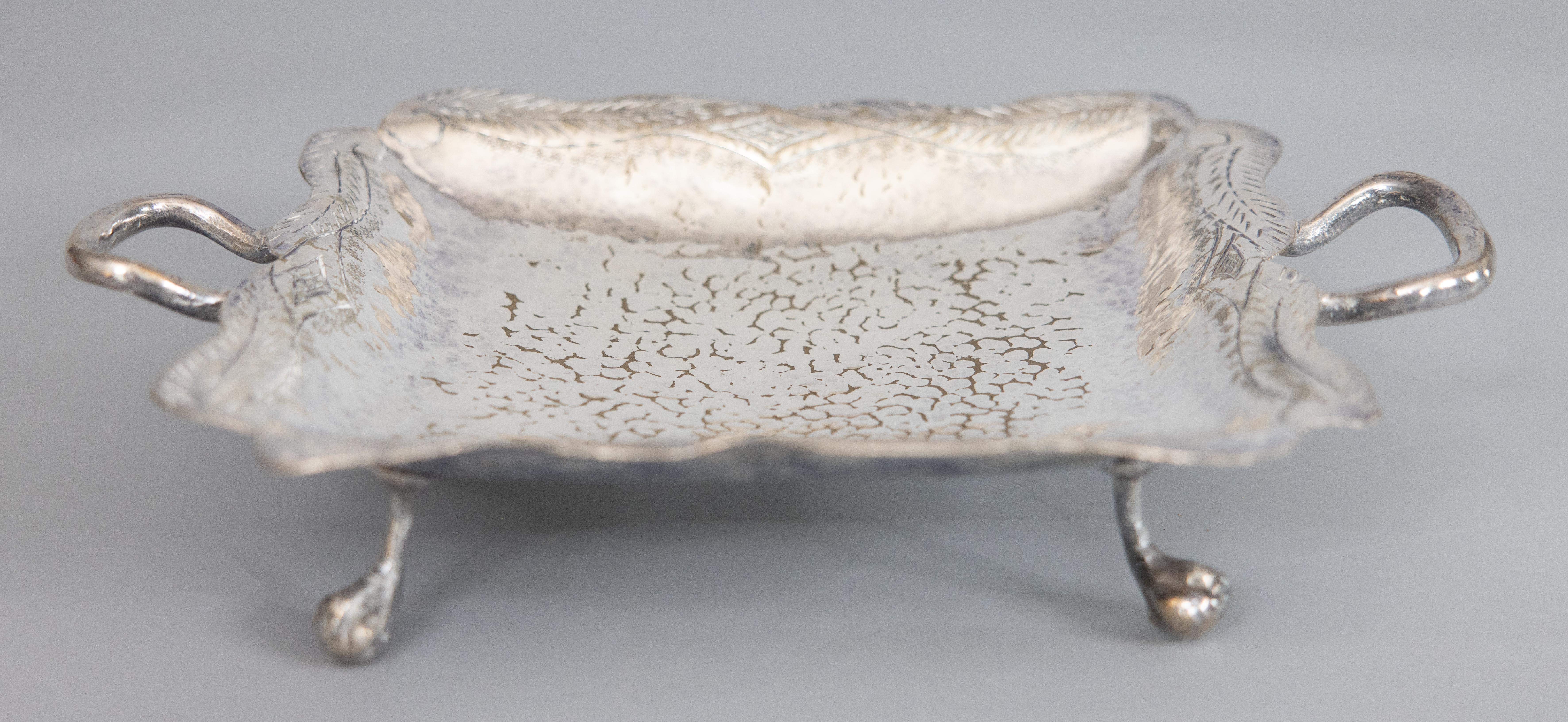 Un elegante vassoio d'epoca con piedi in silverplate martellato, con manici e una bella patina invecchiata. Nessun marchio di fabbrica. Questo splendido vassoio è martellato a mano con un grazioso design smerlato, un bordo di foglie a spirale e