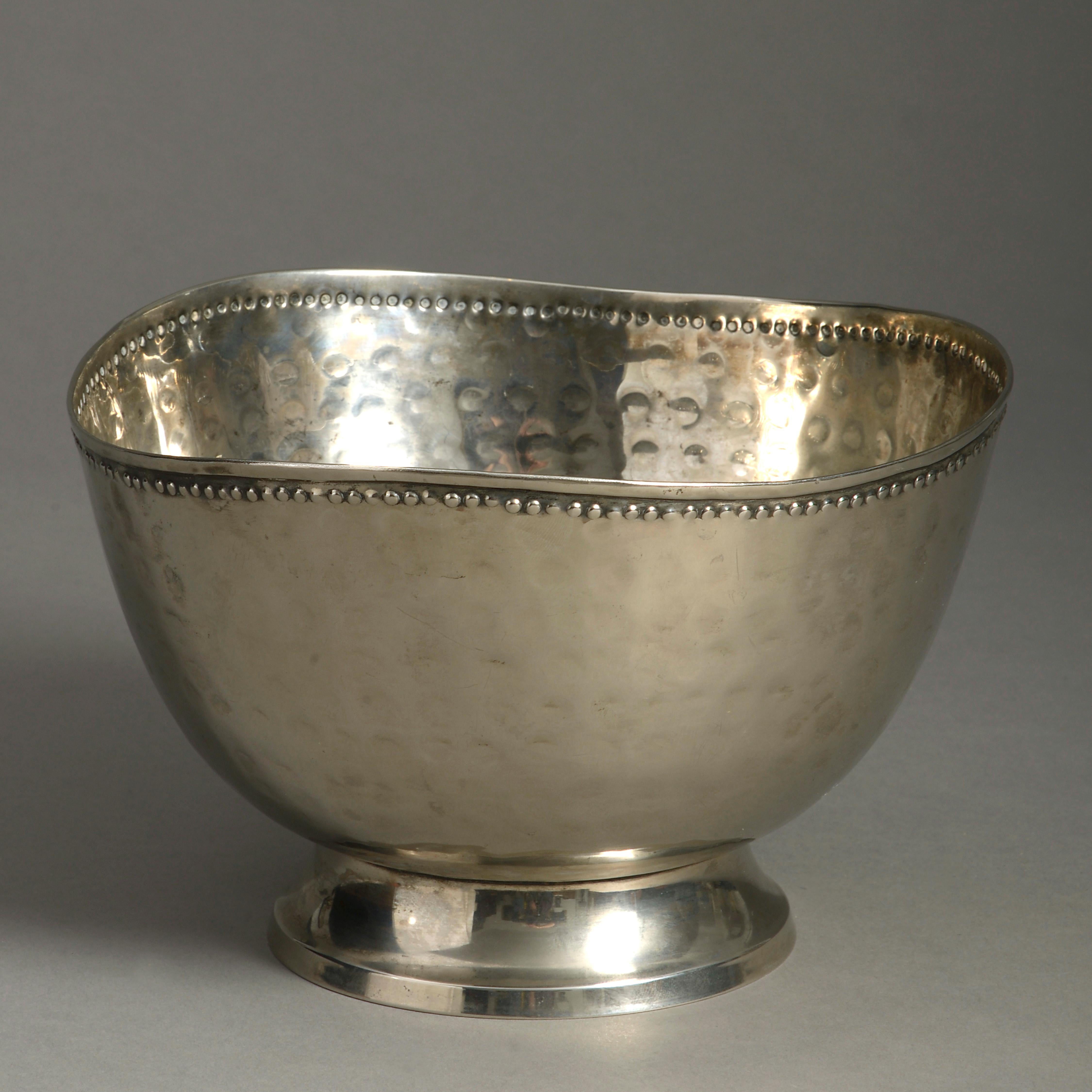 A mid-20th century silver-plated bowl, the body with hammered decoration, the undulating rim with beaded decoration, all set upon a turned foot.

 