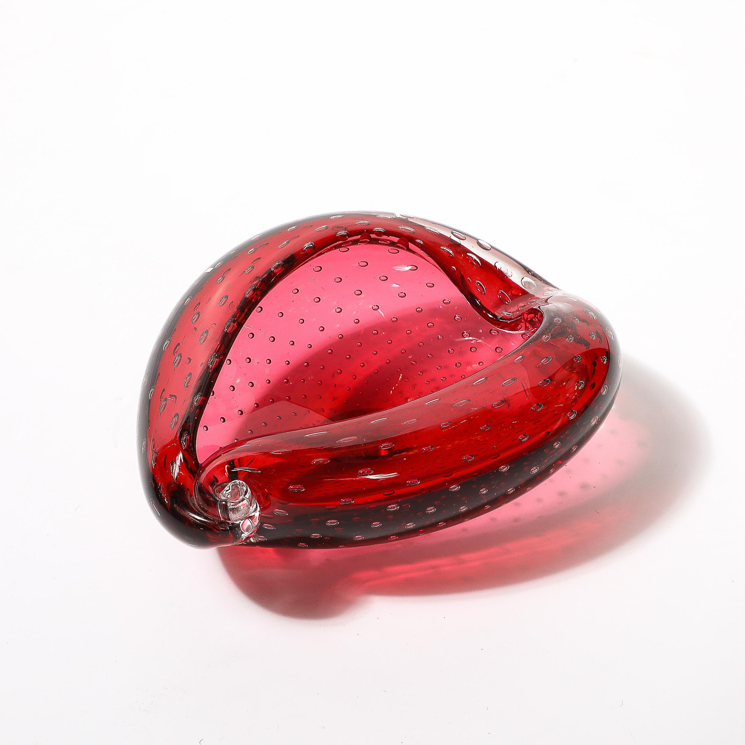 This beautiful mid-century modernist bowl/dish, hand-blown in Murano, Italy circa 1960, showcases a stunning drop form design in vibrant crimson glass. The piece is adorned with intricate bullicante detailing, a technique that incorporates