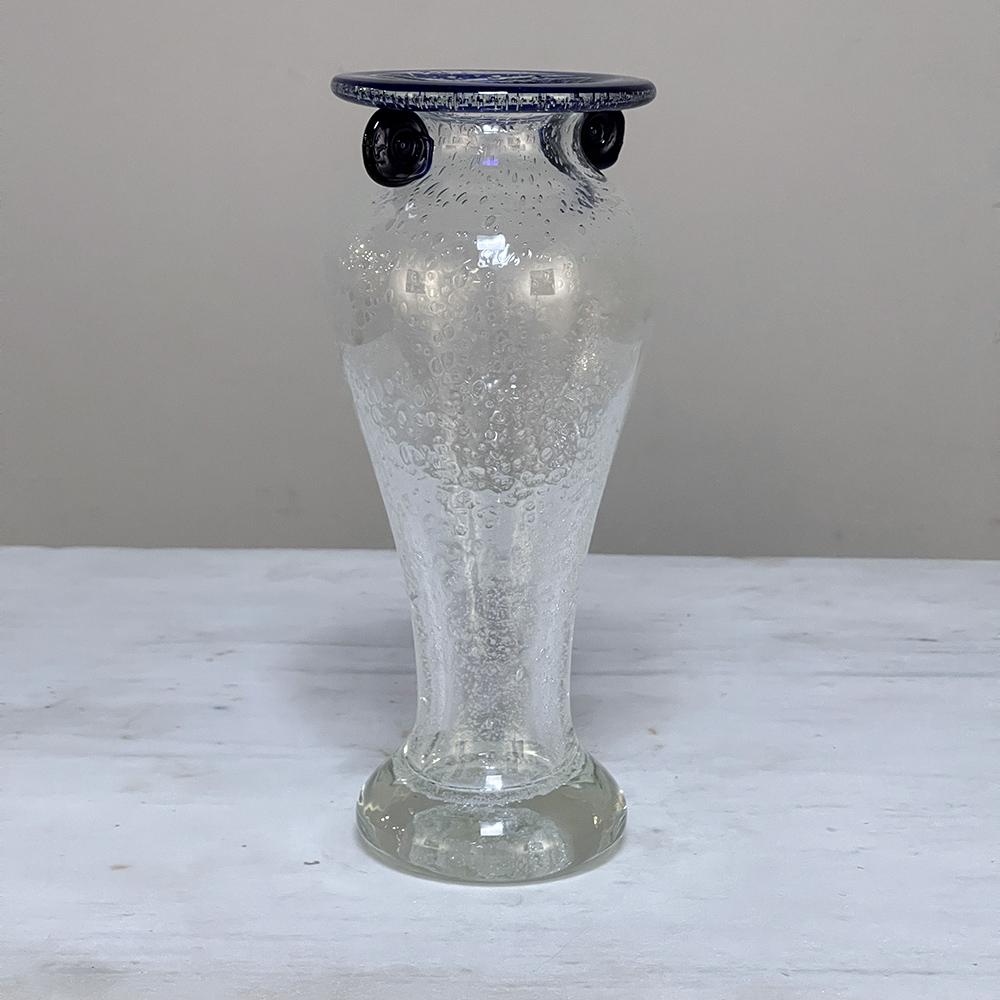 Mid-century hand-blown glass flower vase was created by the master glass crafters of Venice, Italy, and features an intriguing Greek Amphora styling accentuated with a cobalt blue rim with curled volute tabs reminiscent of a Doric capital. The glass