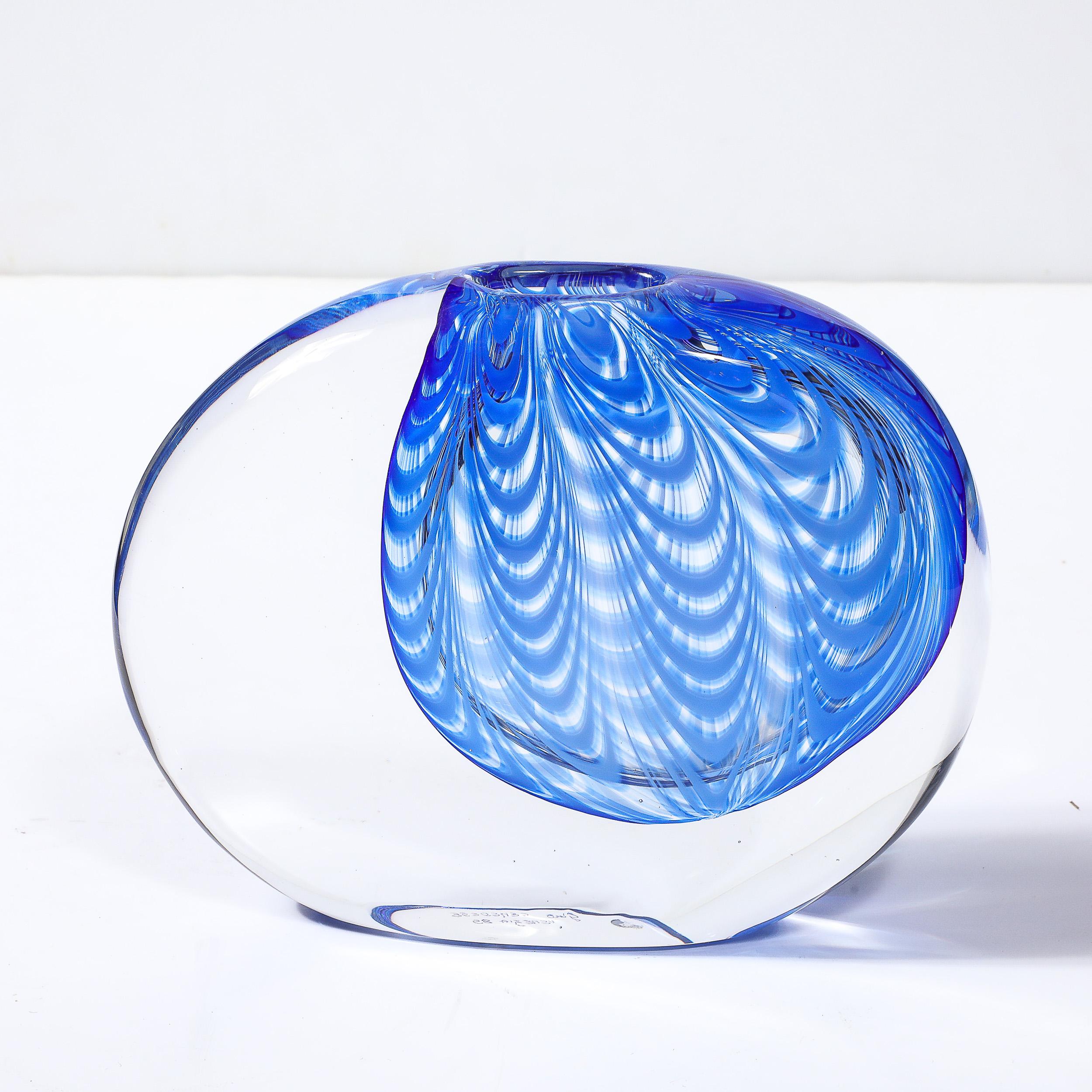 Questo splendido vaso di Murano soffiato a mano in vetro trasparente e cobalto, firmato Cenedese, proviene dall'Italia, C.C. 1985. Questo vaso presenta una composizione rotonda sagomata con lati allungati e appiattiti, con uno splendido dettaglio a