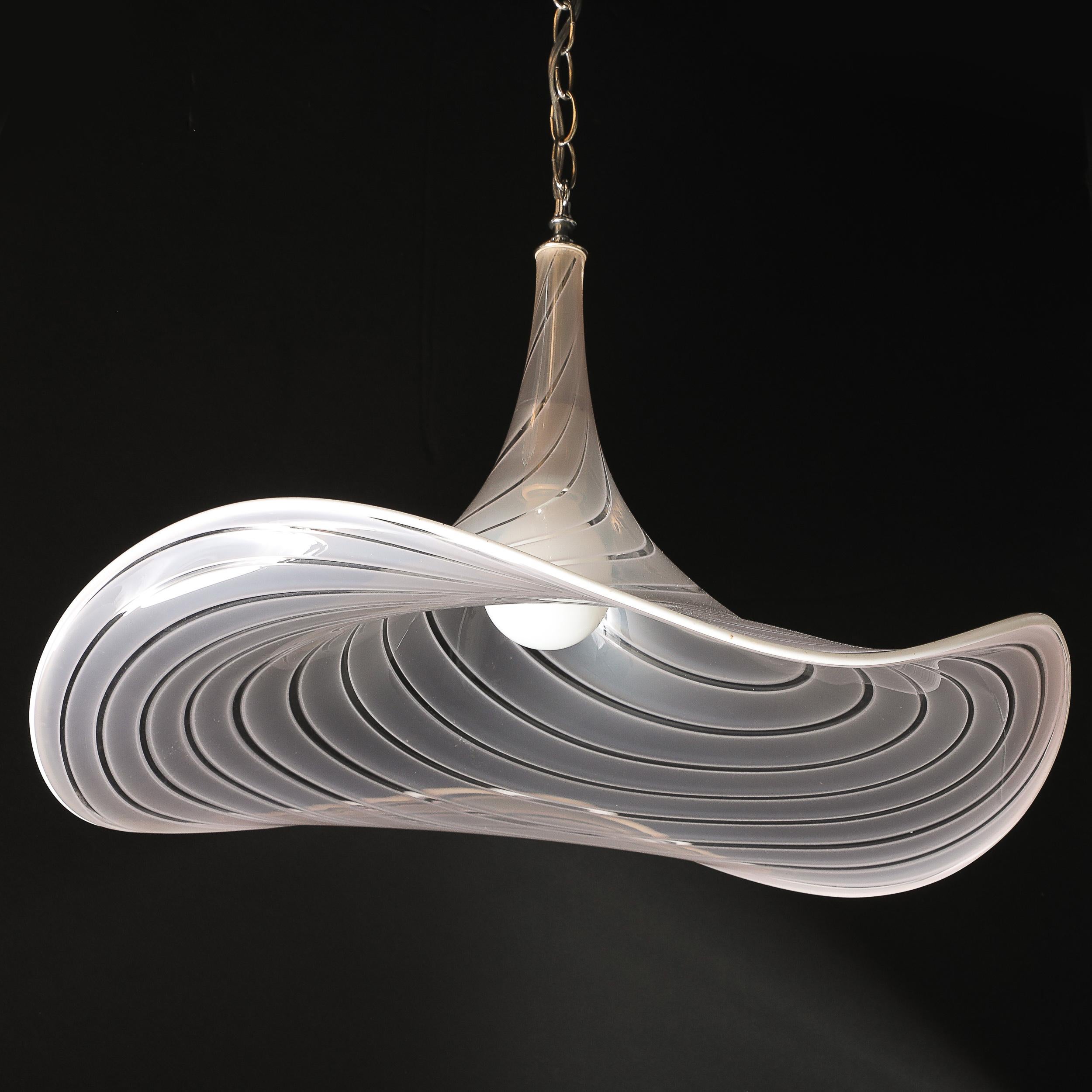 Questo splendido lampadario a sospensione modernista di metà secolo mette in mostra l'eccezionale arte del vetro di Murano soffiato a mano. Realizzato in Italia intorno al 1970, il lampadario presenta un paralume ondulato in vetro rosato, accentuato
