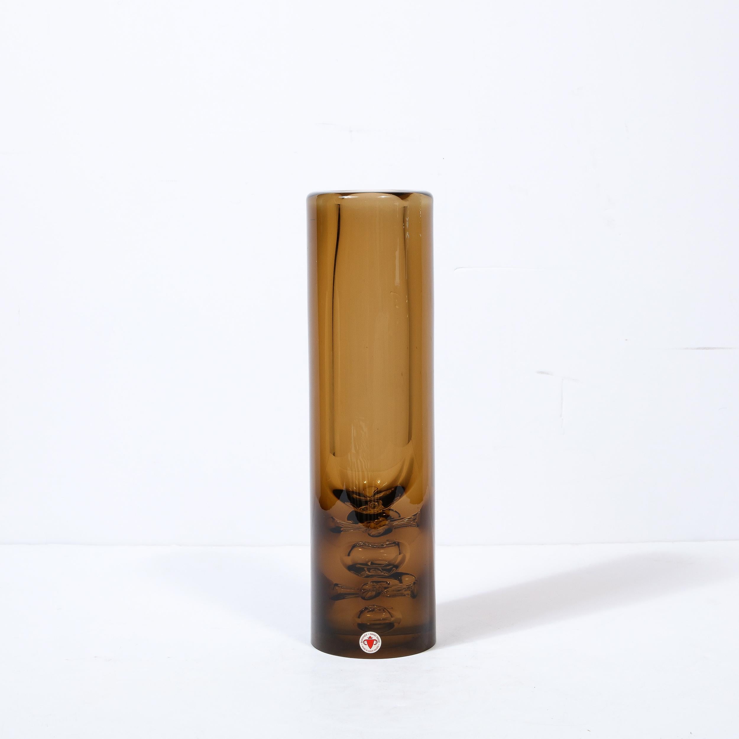 This beautiful Mid-Century Modern hand blown glass vase was realized by the esteemed maker Baranek in the Czechoslovakia circa 1960. It features a cylindrical body in translucent glass in a sumptuous smoked amber hue with prominent Murines
