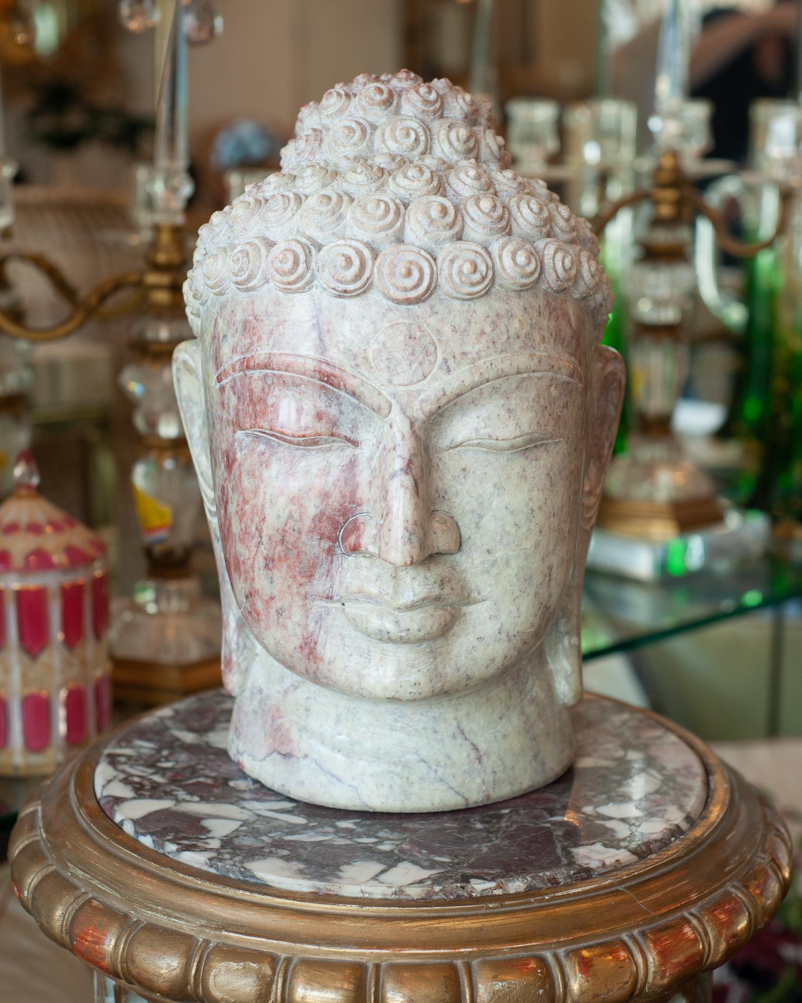A stunning midcentury large hand carved marble Buddha head with exceptional detail. A beautiful addition to any interior, this marble features a variety of tones with red running through the face. The quality of the carving is what makes this