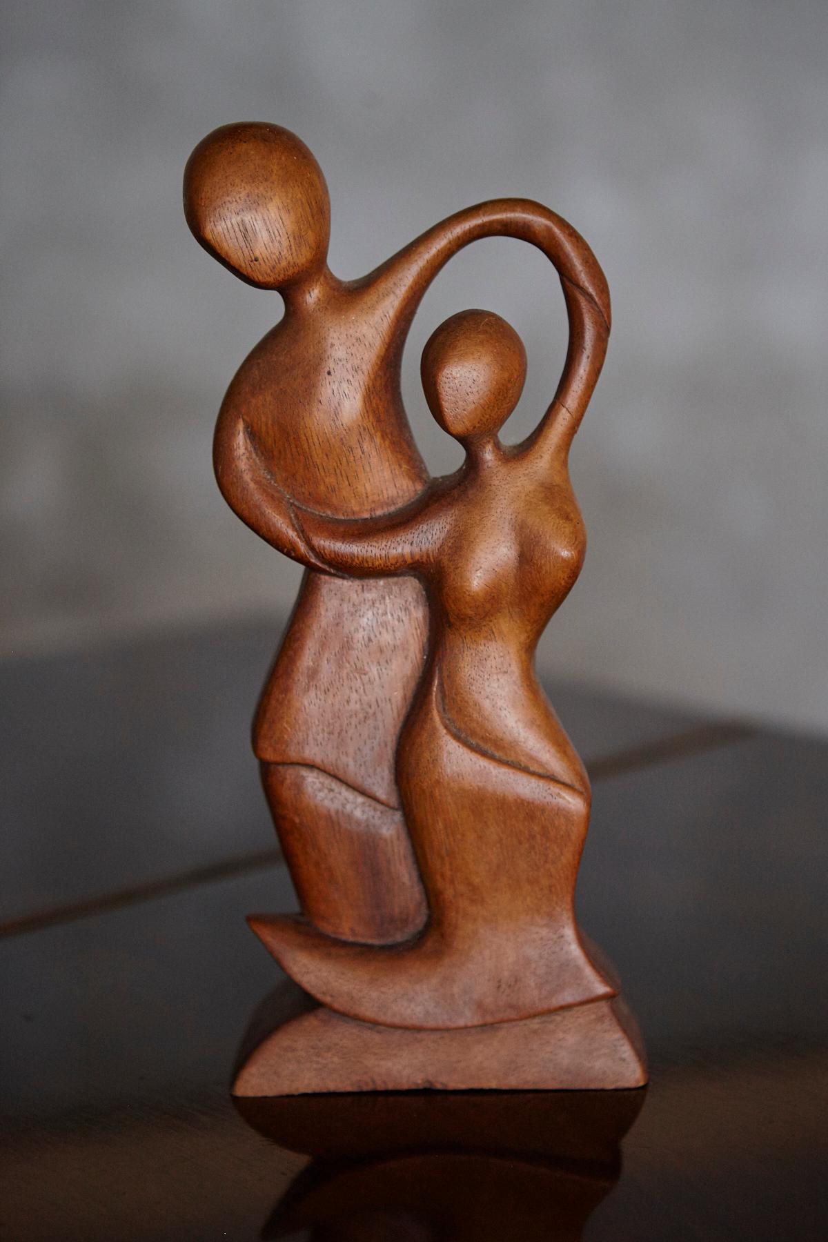 Beautiful mid-century hand-carved wooden sculpture depicting an abstract couple in dance. The flowing lines and organic form capture a sense of movement and intimacy, while the smooth finish highlights the natural grain and warmth of the