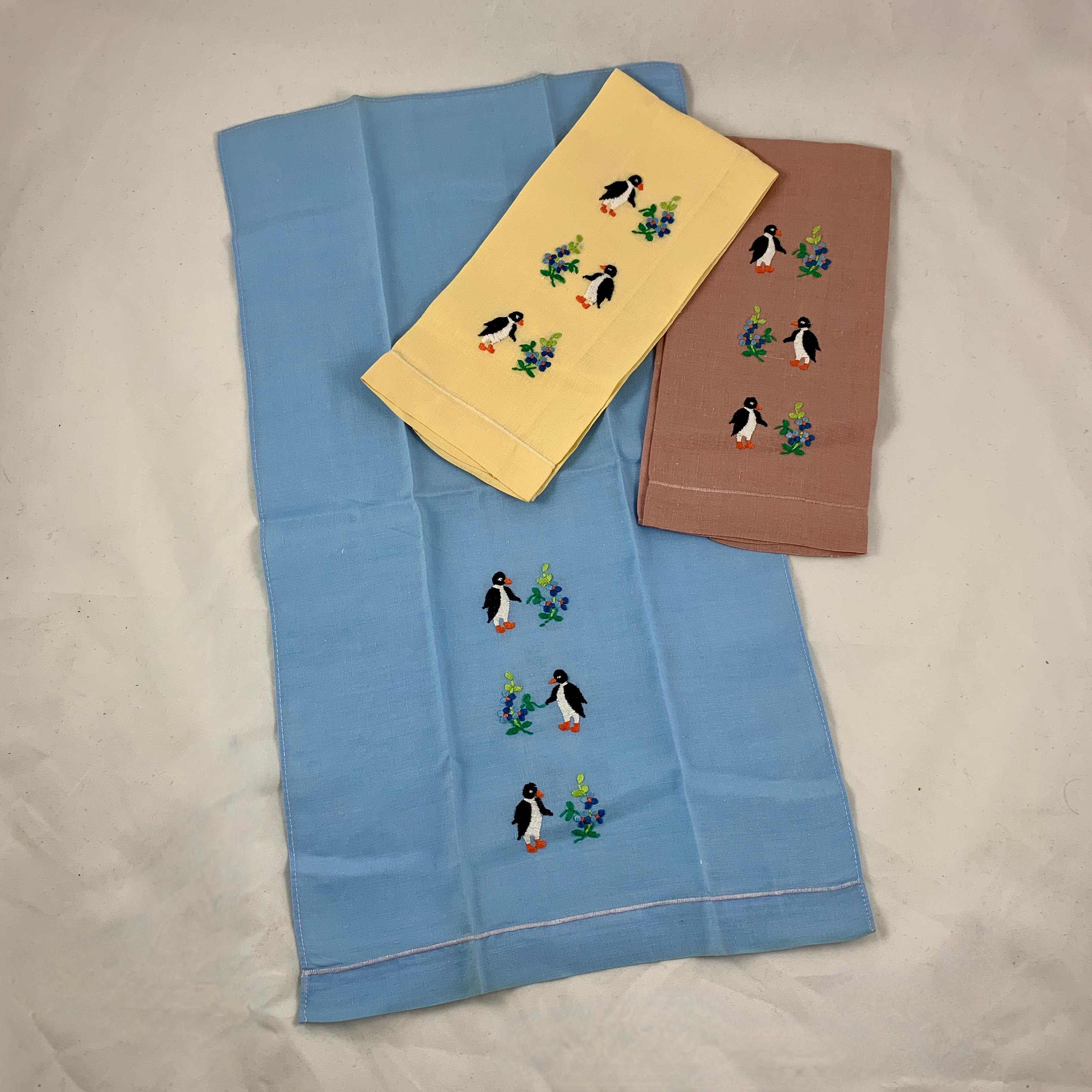 Ein charmantes Set aus drei Gästehandtüchern aus der Mitte des Jahrhunderts, handbestickt mit einem Trio von Pinguinen und Blumensträußen. In Butterblumengelb, Kornblumenblau und ziegelrotem Leinen, schön gestärkt.

Maße: 19 Zoll L x 10 Zoll