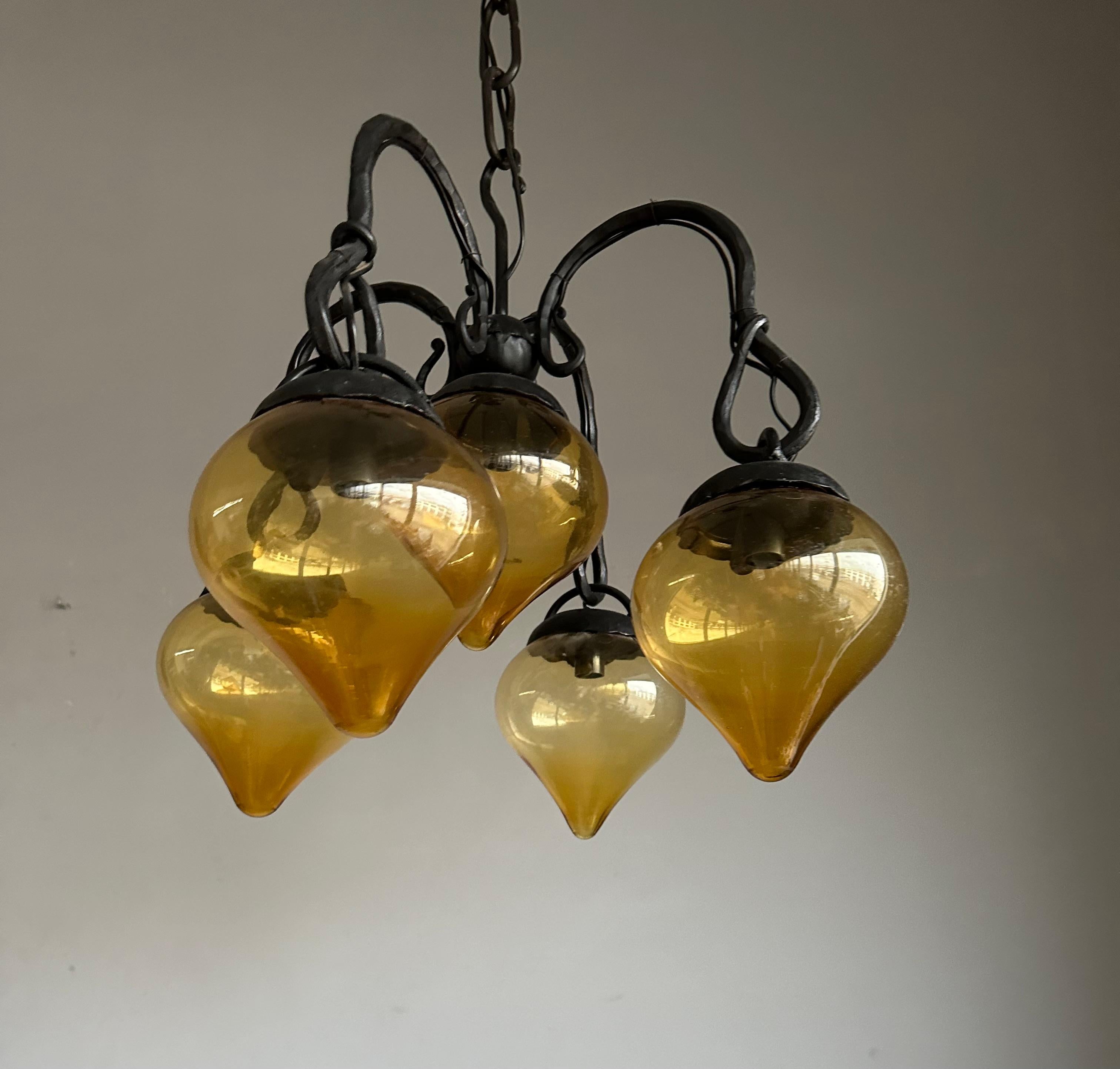 Lustre en fer forgé du milieu du siècle, forgé à la main, avec. Cinq abat-jour en verre soufflé ambré en vente 2