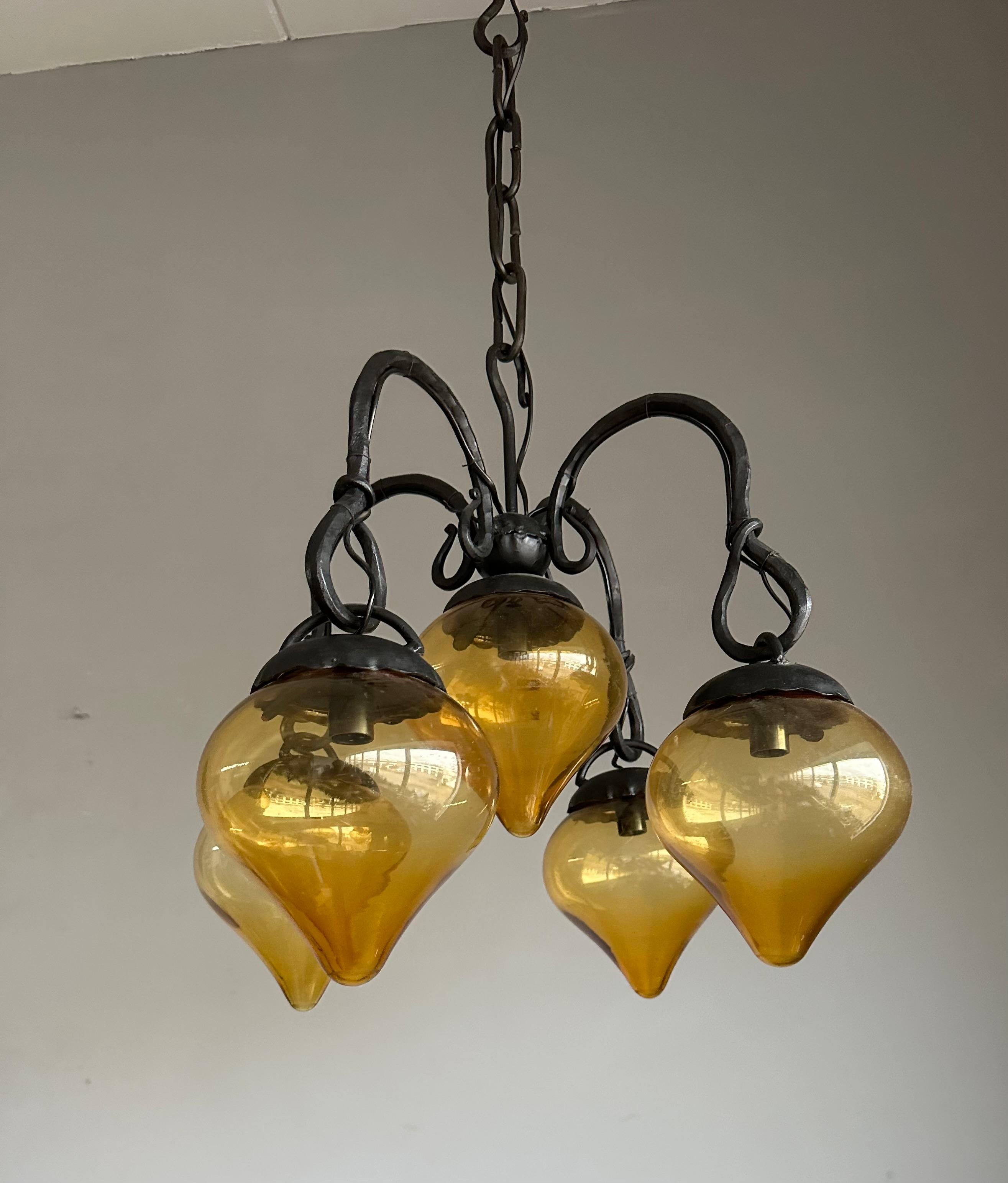 Lustre sculptural du milieu du siècle en fer forgé avec des abat-jours en verre soufflé ambré, années 1960.

Un lustre qui transcende la fonction, ce chef-d'œuvre artisanal du milieu du siècle est une fusion poétique de feu, de verre et de fer.