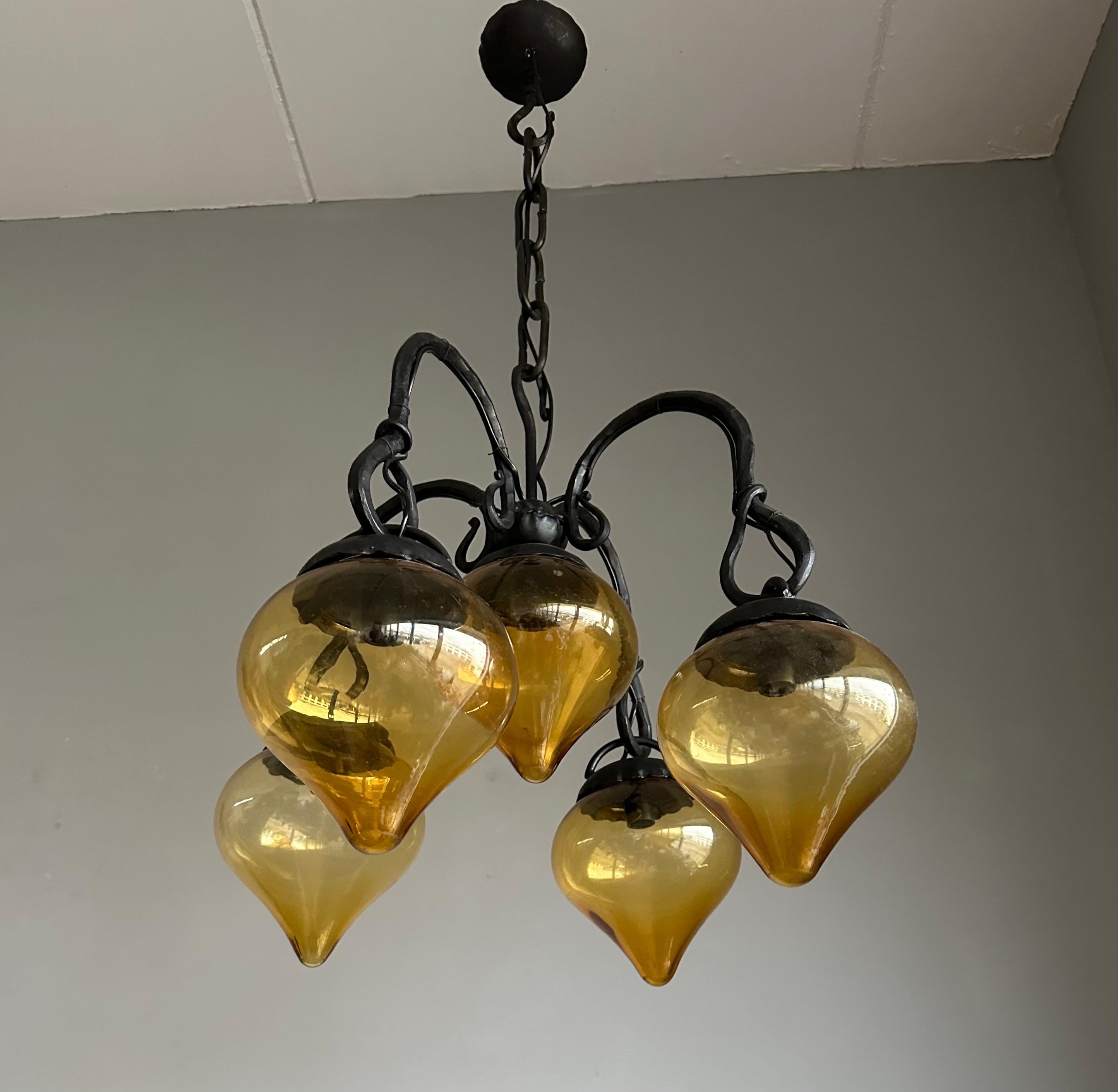 Mid-Century Modern Lustre en fer forgé du milieu du siècle, forgé à la main, avec. Cinq abat-jour en verre soufflé ambré en vente