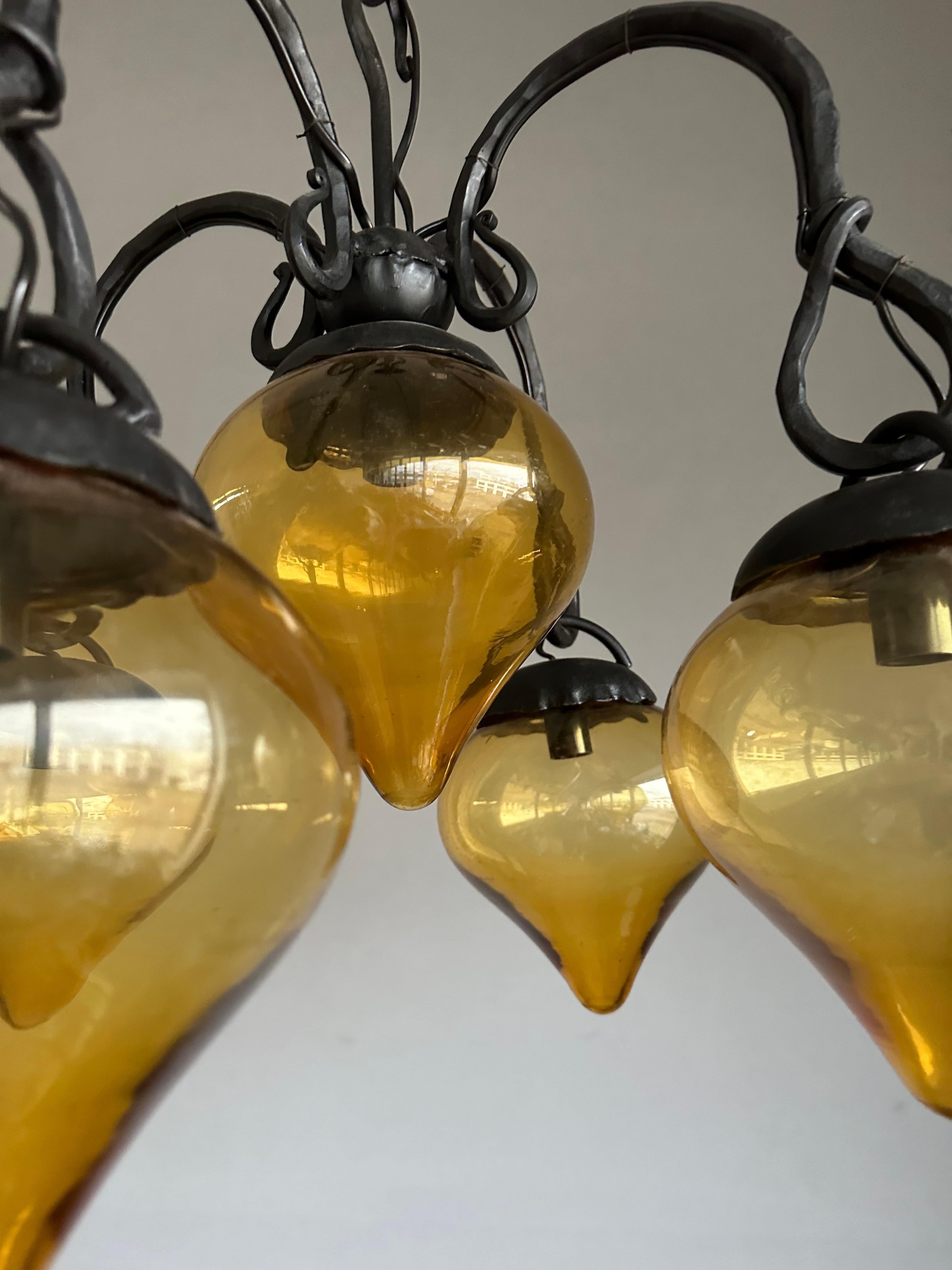 Forgé Lustre en fer forgé du milieu du siècle, forgé à la main, avec. Cinq abat-jour en verre soufflé ambré en vente