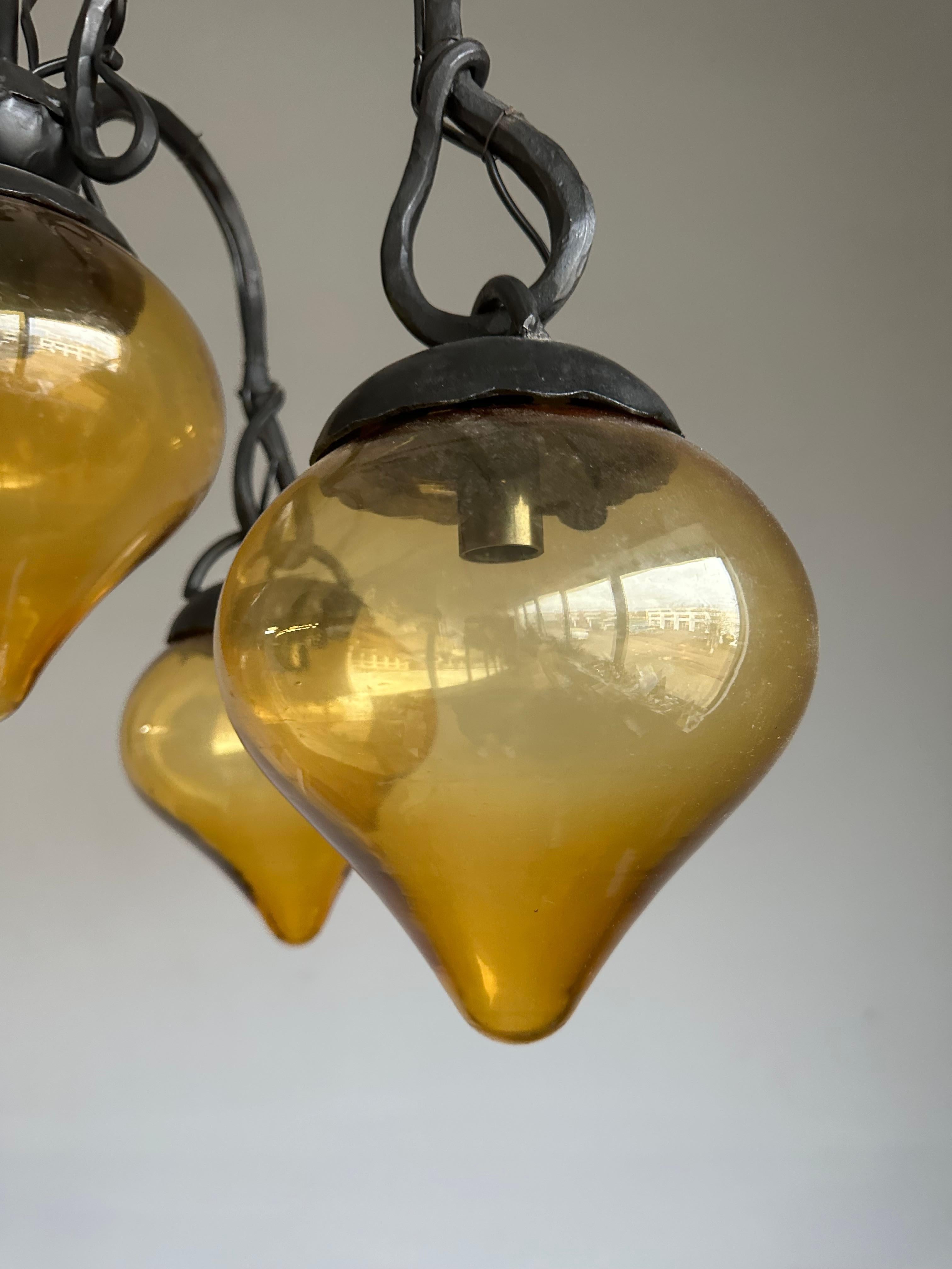 20ième siècle Lustre en fer forgé du milieu du siècle, forgé à la main, avec. Cinq abat-jour en verre soufflé ambré en vente